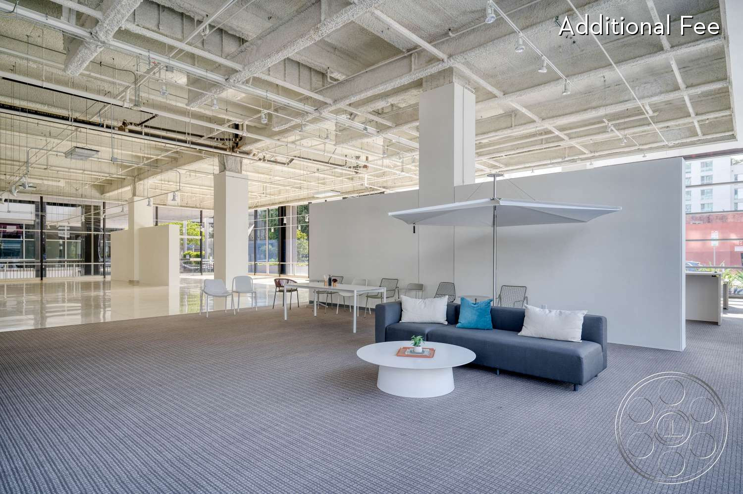 SKYstudio® - large windows, white walls, workspace, exposed ceiling, open floor plan, natural light, minimalist decor, contemporary design, round coffee table, urban setting, flexible layout, gray carpet, sofa with cushions, multifunctional space, creative environment, comfortable seating, metallic fixtures, casual meeting area, scandinavian furniture
