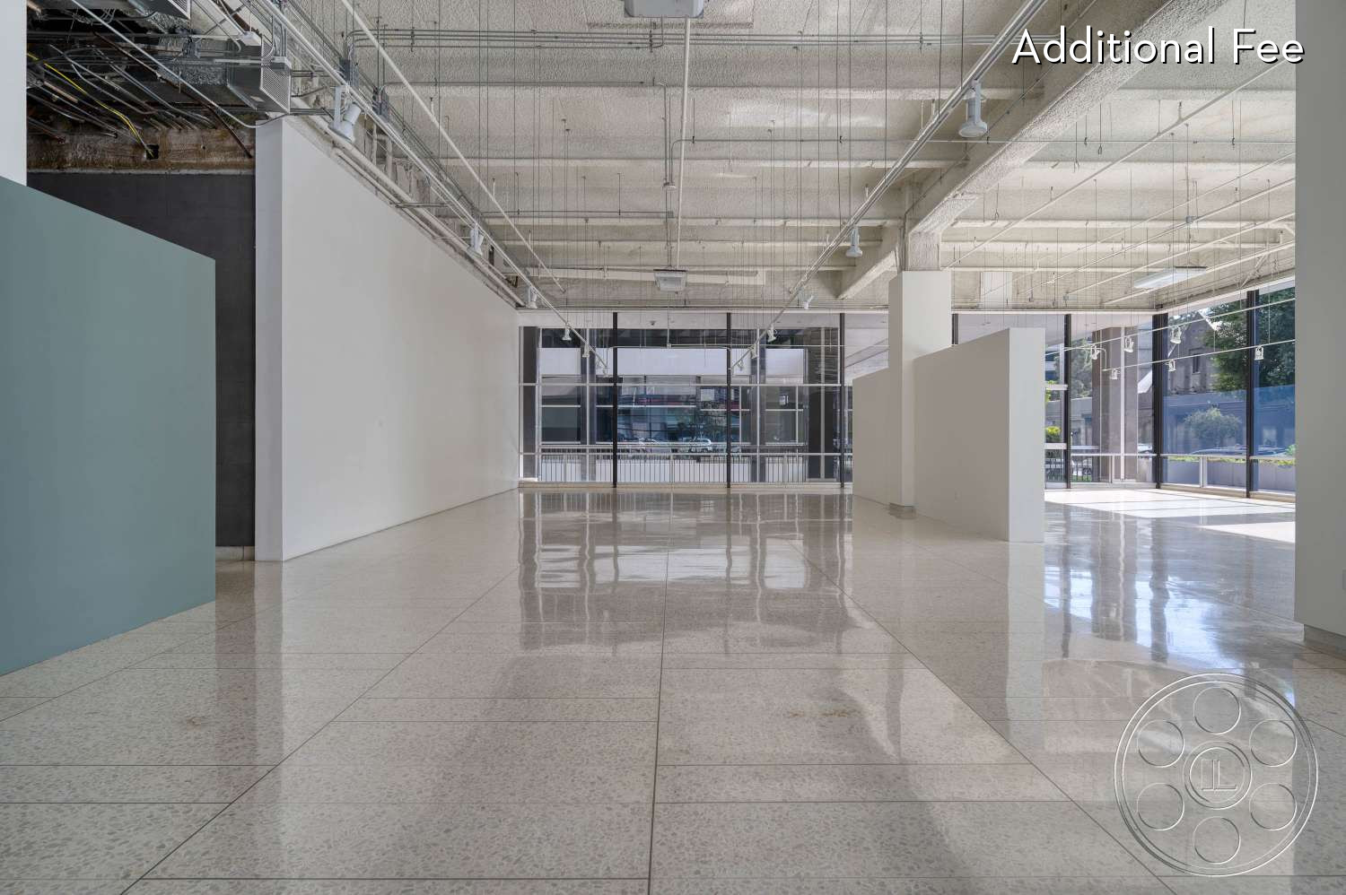 SKYstudio® - large windows, white walls, open floor plan, concrete ceiling, natural light, minimalist decor, neutral color palette, modern design, ambient lighting, flexible layout, versatile space, gallery space, industrial elements, commercial space, polished terrazzo flooring, exposed ductwork, subtle color accents, artistic setting, light-filled environment
