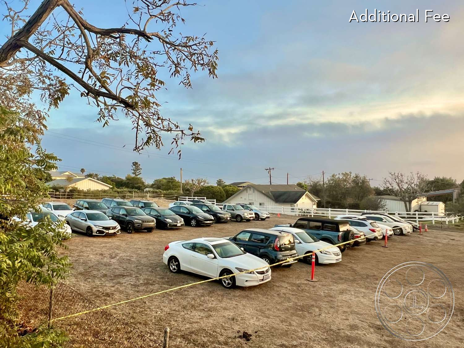 Zen Garden - exterior, minimalist, industrial, outdoor, cars, casual, rural, natural-light, parking-lot, open-space, fenced-area, gravel-surface, white-fence, tree-branches, slightly-cropped-grass, surrounding-vegetation, utility-poles, simple-architecture