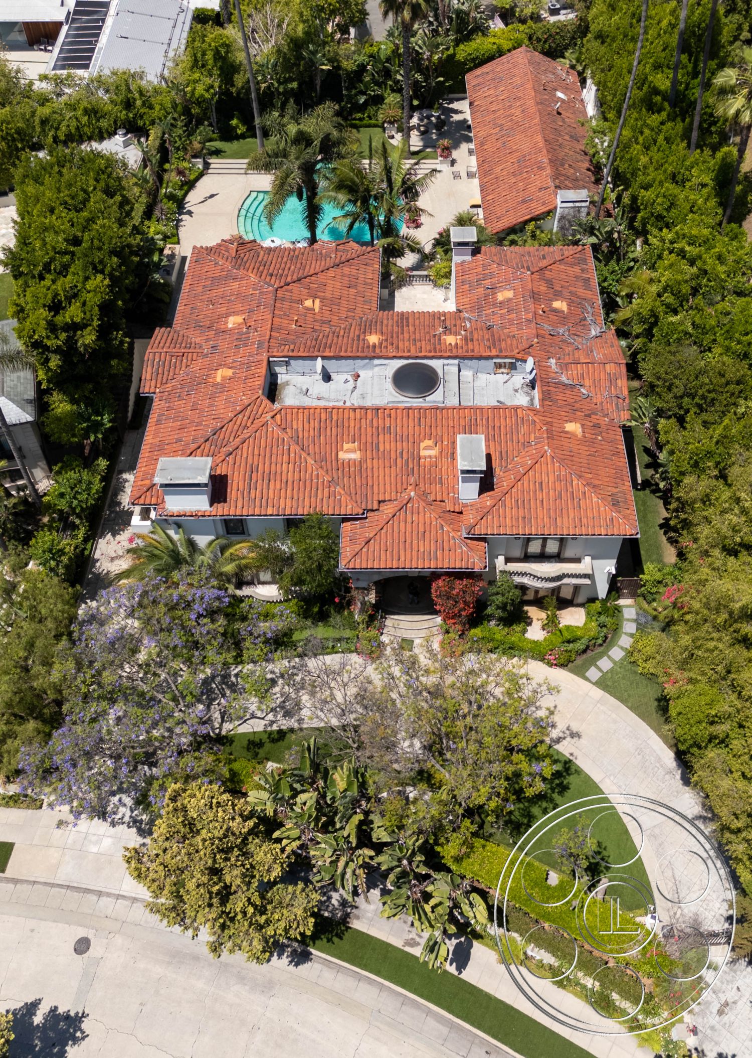 Medit 165 - natural light, exterior, white stucco walls, palm trees, green lawns, outdoor seating area, pool, swimming pool, private retreat, circular driveway, lush landscaping, hardscape, flowering plants, curved pathways, urban oasis, vintage charm, Mediterranean architecture, terracotta accents, red tile roof, stone pathways, luxurious setting, garden pathways, round details, unique rooflines, focal point garden, covered porches