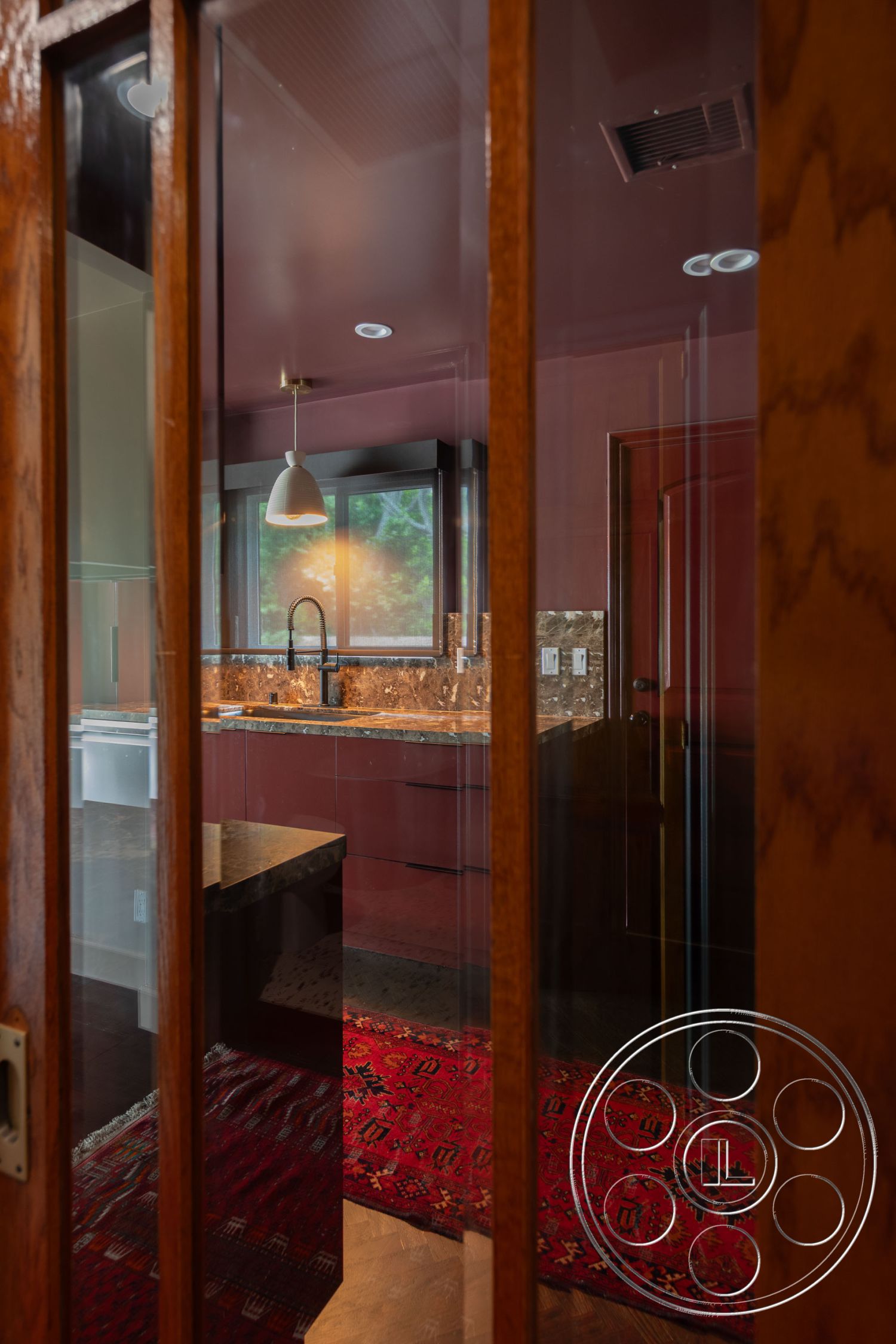 Bungalow 56 - dark wood cabinetry, decorative area rug, stainless steel appliances, textured ceiling, glass panel door, pendant lighting fixtures, interior kitchen with marble countertops, hardwood flooring in the kitchen, rose-colored walls, open-concept kitchen layout, modern kitchen with minimalist design, reinforced glass window views, elegant contemporary decor