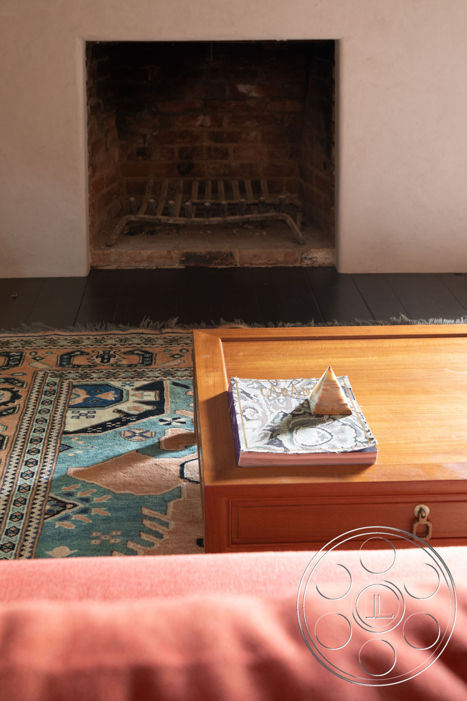 Bungalow 56 - wooden coffee table, rustic decor, ambient lighting, dark hardwood floor, modern rustic style, comfortable seating arrangement, textured plaster wall, exposed brick fireplace surround, handwoven area rug, traditional living room, natural light interior, cozy fireplace setting, sitting area with warm tones, decorative art book display