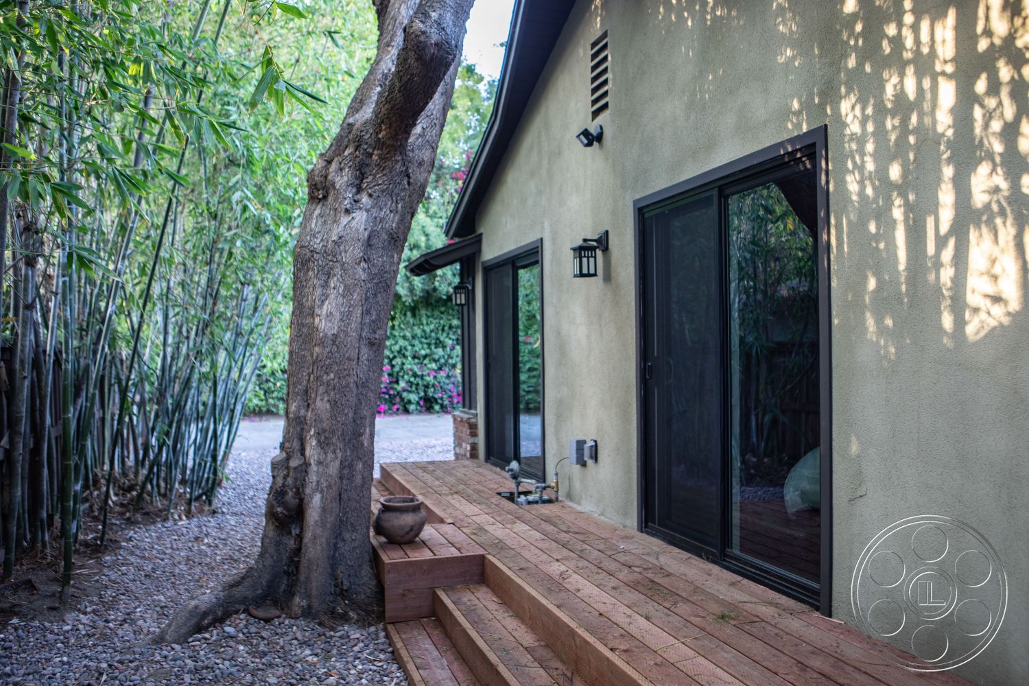 Bungalow 56 - gravel pathway, natural wood railing, contemporary architectural style, exterior wood deck steps, exterior stucco wall, exterior sliding glass doors, exterior wall-mounted lighting, surrounding bamboo landscape, lush garden setting, tree-lined exterior, outdoor space with privacy, casual outdoor living environment