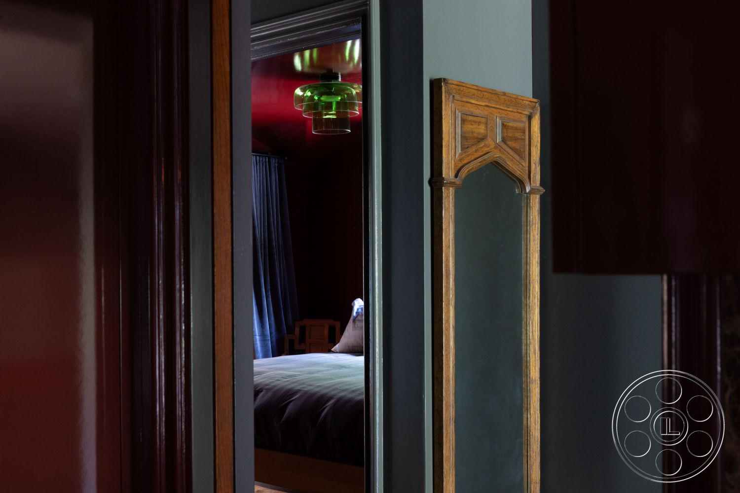 Bungalow 56 - interior wood paneling, interior recessed lighting, interior plush bedding, interior dark wood trim, interior framed mirror with Gothic arch, interior textured wallpaper, interior velvet drapes, interior soft lighting fixture, interior hardwood flooring, interior painted walls in deep hues, interior coffered ceiling details, interior bedroom with modern aesthetic, interior open doorway, interior dark color palette, interior contemporary bedroom design