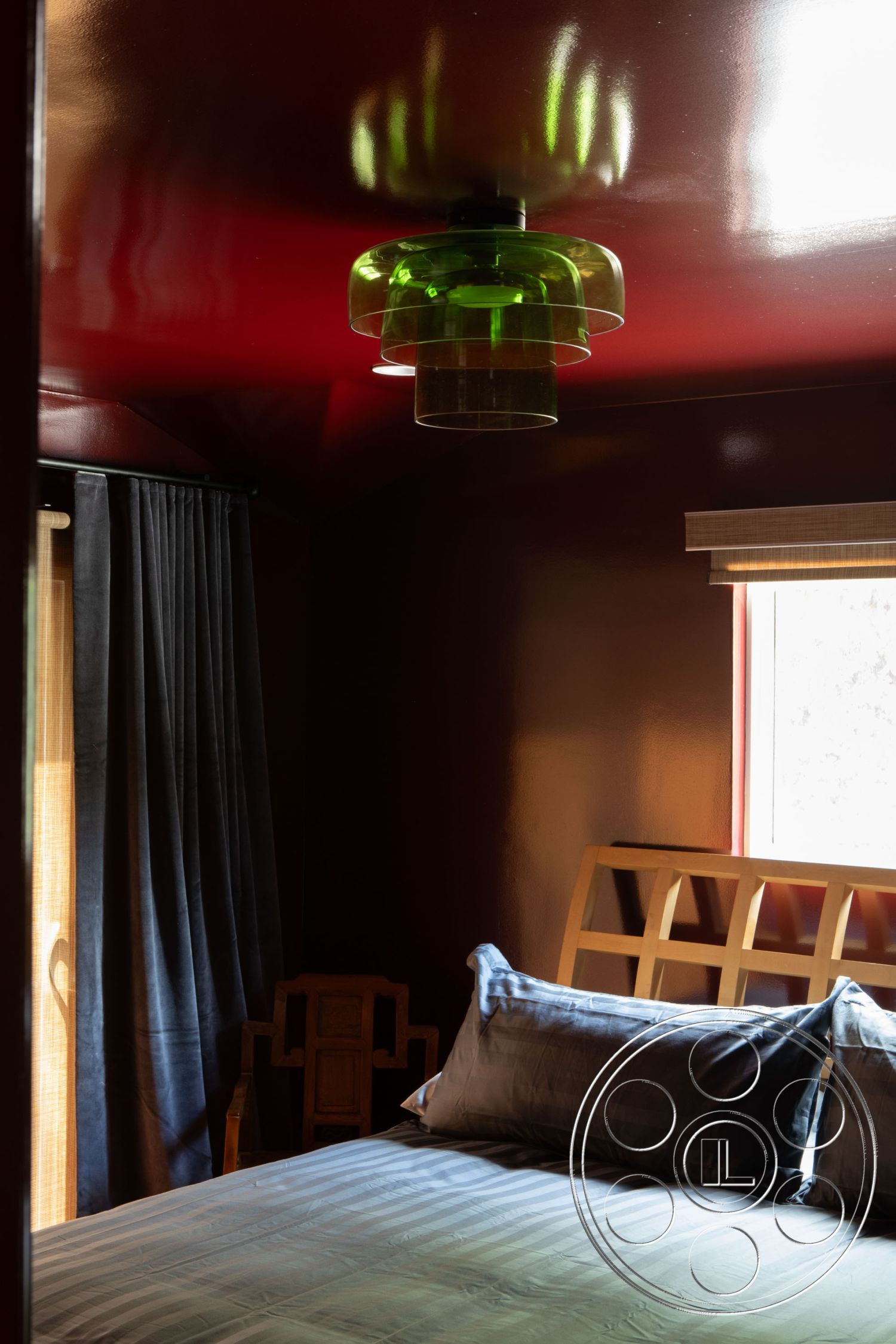 Bungalow 56 - minimalist decor, cozy atmosphere, warm color palette, modern aesthetic, natural light from window, striped bedding with gray tones, interior bedroom with red gloss ceiling, green glass pendant light fixture, dark blue velvet curtains, wooden slat headboard, elegant chair in traditional design