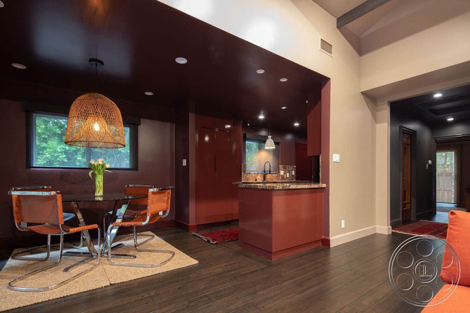 Bungalow 56 - interior open-concept layout, interior hardwood living room floors, interior marble kitchen countertops, interior exposed wood ceiling beams, interior round glass dining table, interior woven pendant lighting, interior textured wall panels, interior dark painted accent walls, interior stainless steel kitchen appliances, interior chrome and leather dining chairs, interior recessed ceiling lighting, interior large windows with black frames, interior area rug under dining table, interior modern kitchen design, interior contemporary furniture style