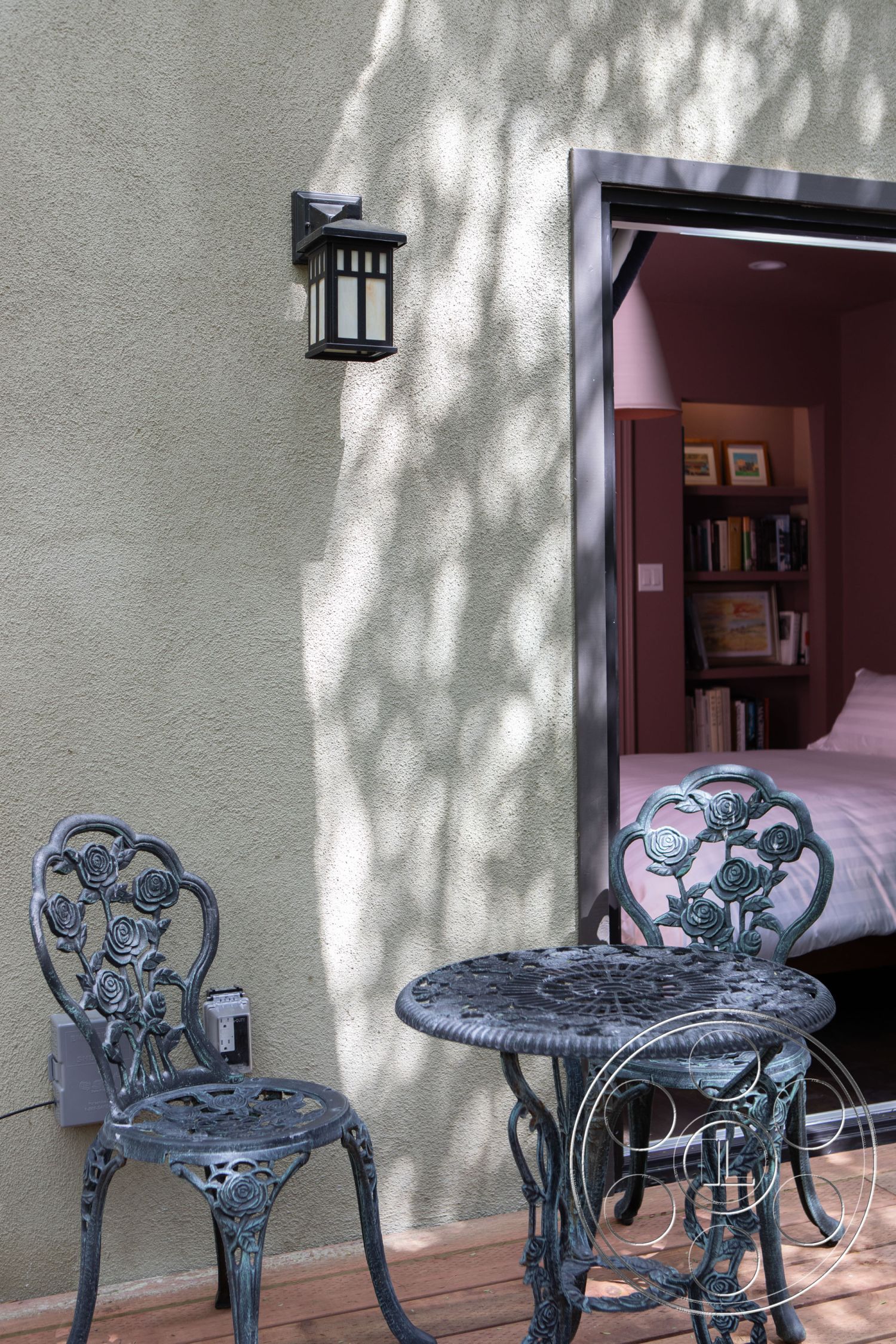 Bungalow 56 - outdoor seating area, garden setting, textured wall treatment, contemporary outdoor space, wooden deck flooring, exterior stucco wall finish, cast iron bistro table, cast iron chairs, decorative wall lantern, modern sliding glass door, framed interior view, shaded patio area, urban outdoor retreat