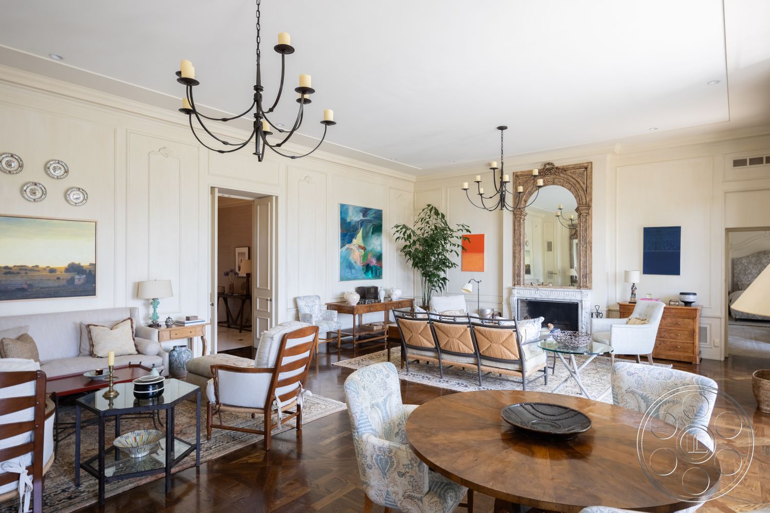 The Regent - neutral color palette, open floor plan, artistic wall decor, abstract wall art, glass coffee table, wood dining table, large windows for natural light, textured plaster walls, patterned area rug, upholstered armchairs, exposed wood ceiling beams, hardwood living room floors, traditional chandelier lighting, ornate framed mirror, decorative tableware, plant accent, elegant wall moldings, classic style furniture, walk-through doorway, living room seating area, sitting room
