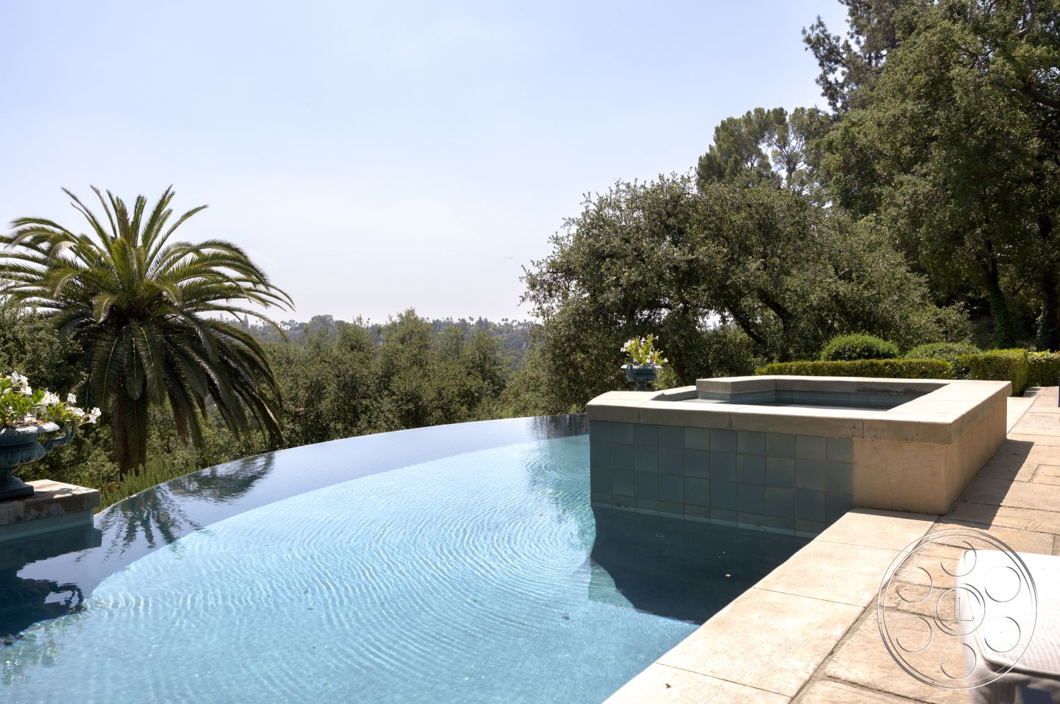 The Regent - surrounding greenery, modern water feature, outdoor relaxation area, scenic hillside view, landscaped garden setting, exterior infinity pool, concrete pool patio, blue tile spa, natural stone pool deck, poolside palm trees, stone retaining walls, luxury outdoor living space