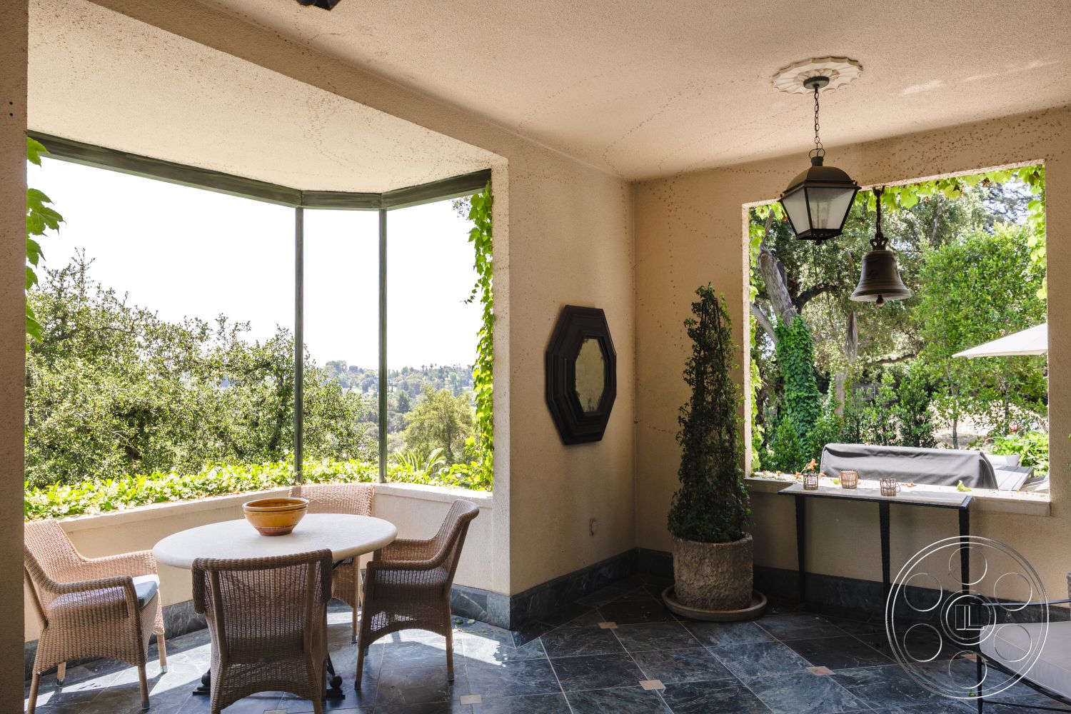 The Regent - hanging pendant light, surrounding lush greenery, modern outdoor dining area, exterior patio with slate flooring, wicker dining chairs, glass window wall with panoramic view, stucco wall treatment, planter with topiary, octagonal-shaped table, urban hillside setting