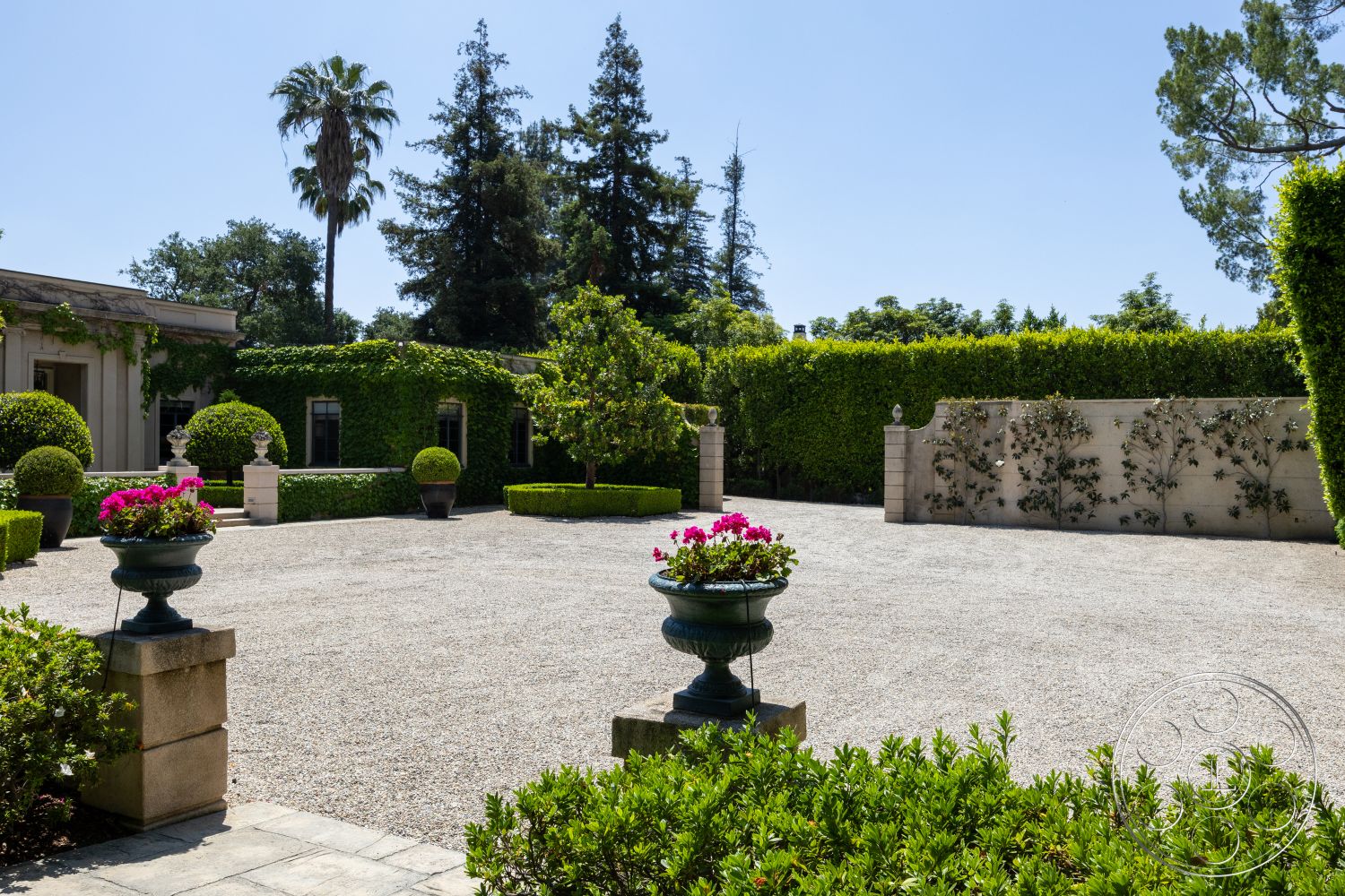 The Regent - low-maintenance landscaping, gravel driveway, tropical palm trees, formal garden design, sunny outdoor space, smooth stone pathway, hedge privacy wall, lush green shrubbery, brick flower bed borders, potted flowering plants, decorative stone garden wall, outdoor patio setting, modern home exterior, manicured garden area, natural landscape surroundings