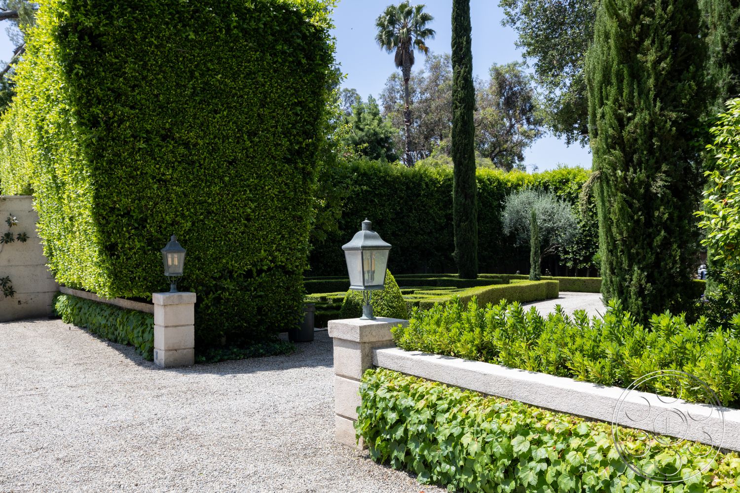 The Regent - surrounding residential neighborhood, gravel driveway, formal garden design, garden seating area, outdoor lighting fixtures, textured stone pathway, lush greenery setting, exterior landscape design, stone garden wall, manicured lawn area, boxwood hedge garden, modern garden lanterns, cypress trees lining path, low-maintenance shrub border, ornamental grasses plantings, architectural garden layout, palms against urban backdrop