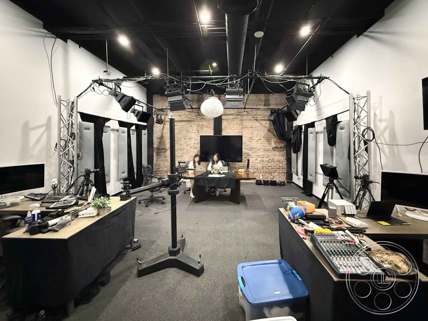 Office 124 - textured carpet flooring, exposed brick accent wall, black acoustic paneling, industrial studio space, black-painted ceiling, soft LED studio lighting, hardwood studio flooring, metal lighting rig, wall-mounted monitors, functional workspace design, multimedia production area, open layout studio, cable management systems, adjustable lighting fixtures, modern audio equipment, creative workspace interior