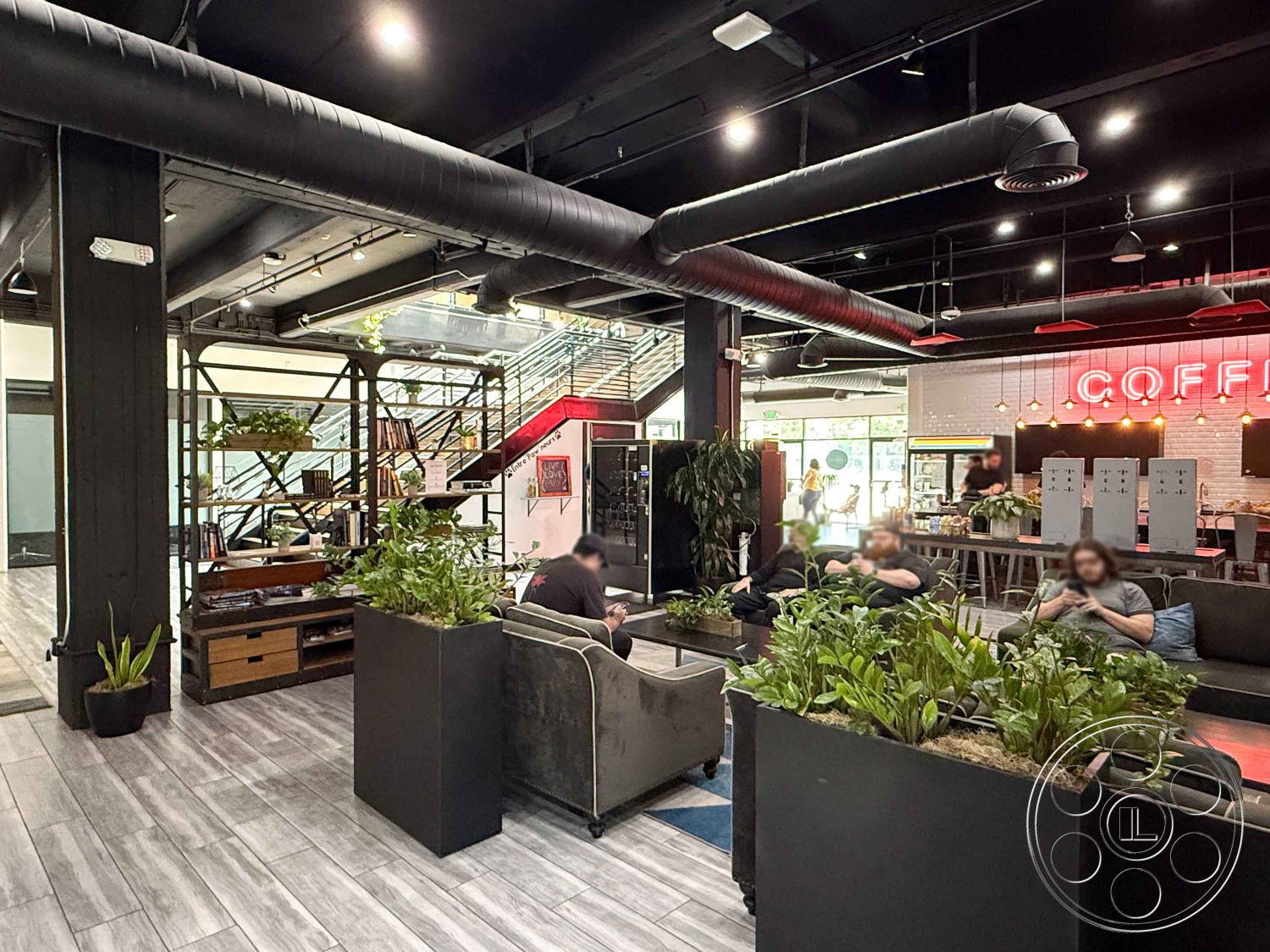 Office 124 - open floor plan, soft seating, polished concrete flooring, large glass windows, textured wall panels, exposed ductwork, cozy sitting area, reclaimed wood accents, wooden shelving units, potted indoor plants, modern furniture arrangement, industrial-style interior, exposed metal ceiling beams, metal stair railing, black steel support columns, LED pendant lighting, contemporary lounge space, urban coffee shop, suburban workspace interior, bright coffee shop ambiance, multi-functional communal space