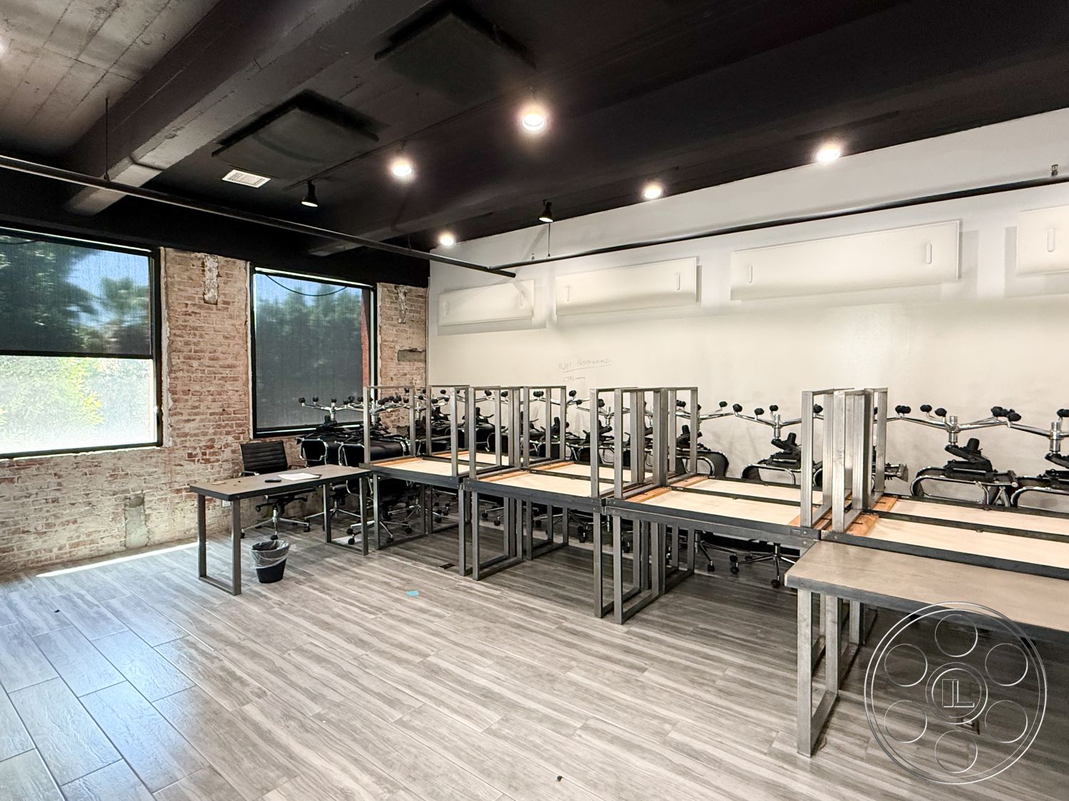 Office 124 - polished concrete floor, exposed brick walls, minimalist furniture design, modern office design, black metal ceiling beams, industrial style lighting fixtures, grey laminate flooring, open layout studio space, large windows with blackout shades, meeting area with metal tables, urban interior space, workspace for fitness classes, contemporary wall decor, natural light environment