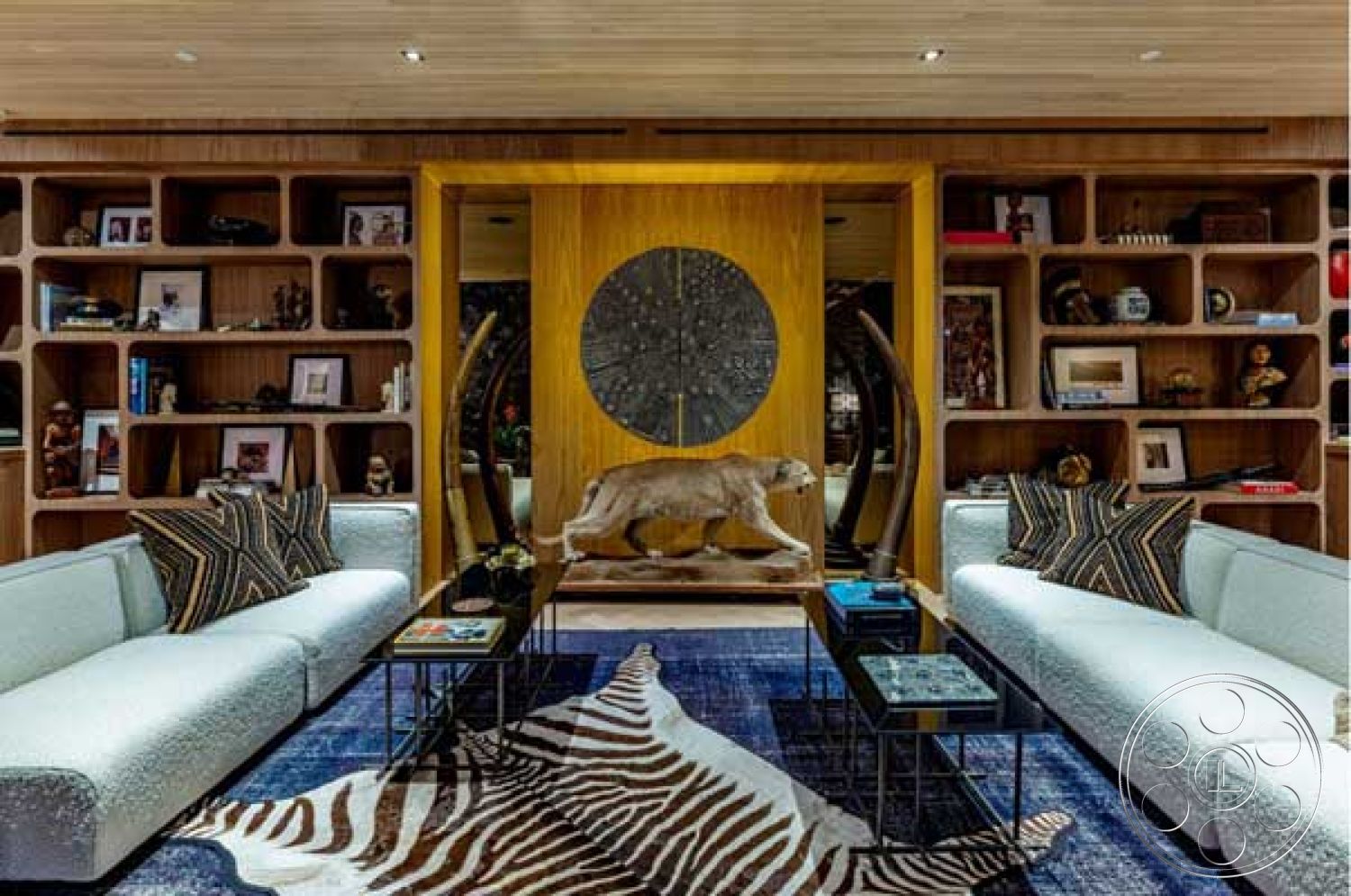 Modern 507 - modern light fixtures, dark wood paneling, interior living room, exposed wood ceiling, built-in wooden bookshelves, textured wool area rug, contemporary upholstered sofas, decorative animal hide rug, geometric coffee tables, feature wall with circular wood detail, soft white painted walls, sophisticated modern decor