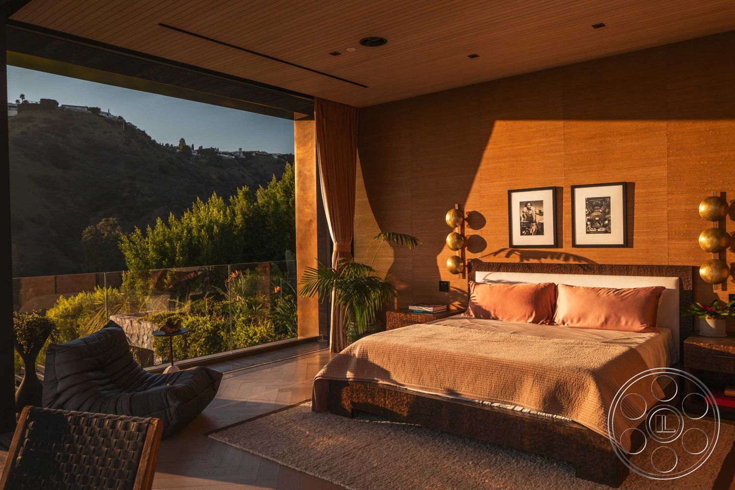 Modern 507 - open concept layout, earth-toned color palette, woven rattan chair, mountain view setting, floor-to-ceiling glass windows, panoramic hillside view, interior bedroom with hardwood flooring, exposed wood paneling wall treatment, contemporary modern style, textured fabric bedding, modern minimalist furniture design, decorative gold pendant lighting, organic accent plants, natural light filled interior, abstract wall art decor