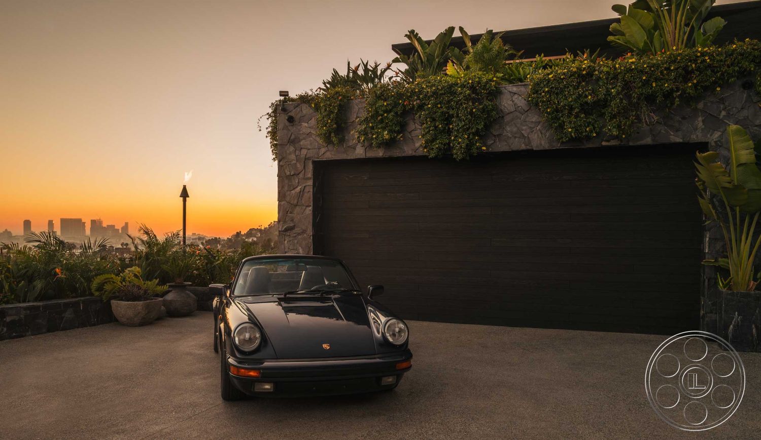 Modern 507 - exterior, modern architectural style, city skyline view, outdoor lighting features, decorative stone planters, stone garage wall, black wooden garage door, stamped concrete driveway, tropical plant landscaping, dimensional stone veneer, poured concrete surface
