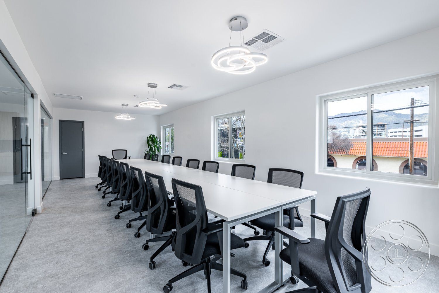 Office 125 - neutral color palette, smooth concrete flooring, ambient natural light, ergonomic office chairs, modern minimalist design, white painted walls, glass partition wall, rectangular conference table, interior conference room, LED pendant lighting, large windows with mountain view