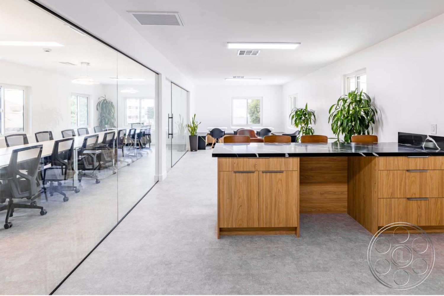 Office 125 - minimalist design elements, natural light from large windows, contemporary lighting fixtures, light grey carpet flooring, open concept workspace, functional office layout, modern office chairs, interior kitchen island with black granite countertop, exposed wood kitchen cabinets, glass conference room partition walls, plants for interior decoration, spacious meeting area, neutral color palette walls, effective use of natural materials