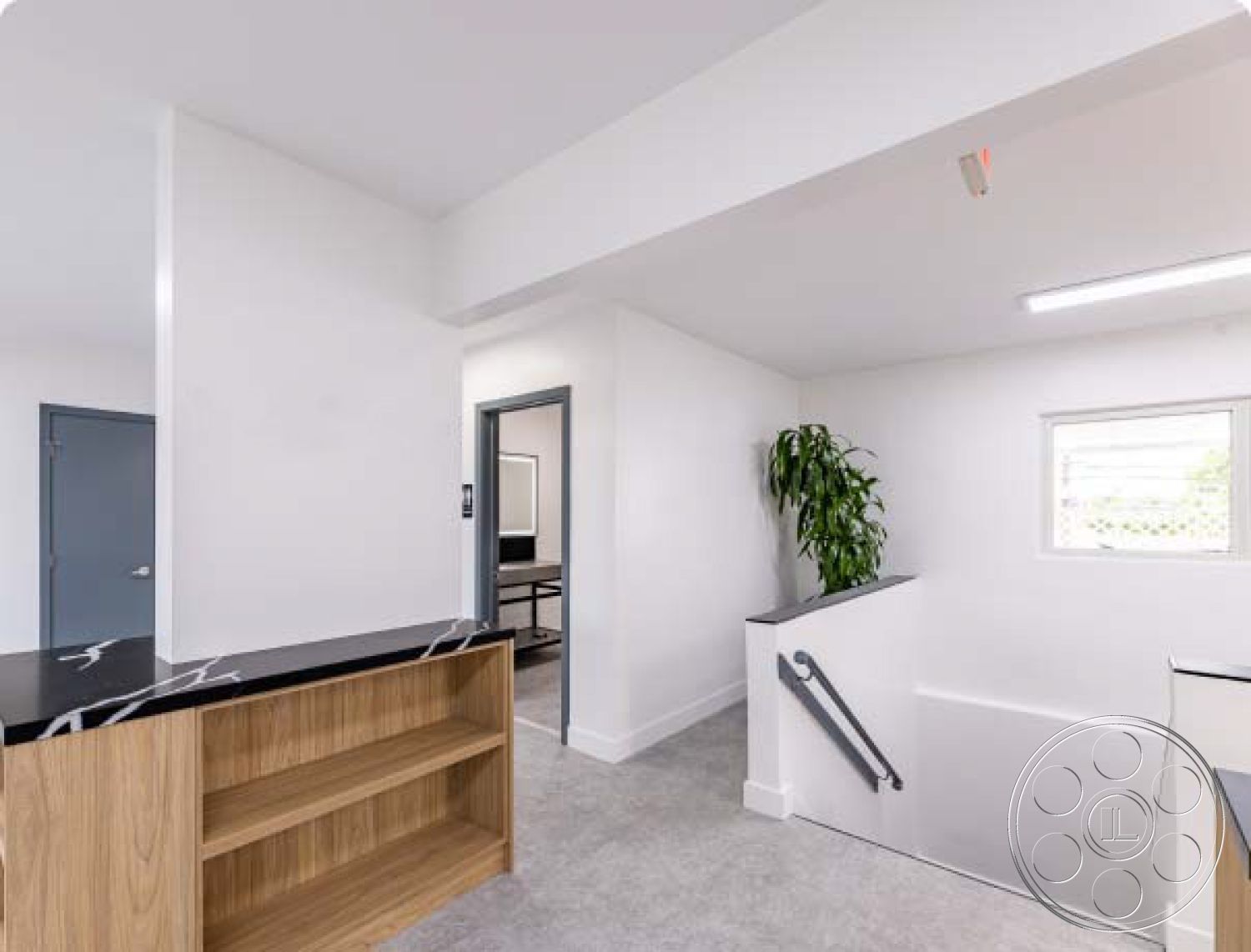 Office 125 - neutral color palette, recessed lighting, modern entryway, black marble countertop, indoor plant decor, open floor plan design, smooth white painted walls, functional workspace area, natural wood shelving unit, light gray concrete flooring, minimalist staircase railing, window with modern trim