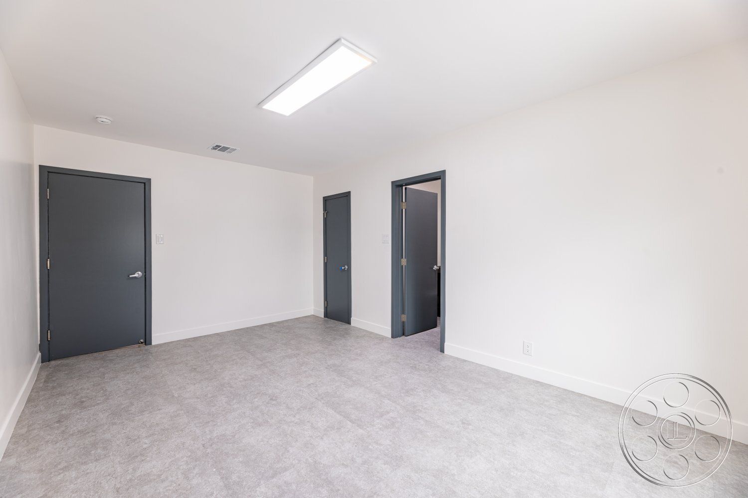 Office 125 - neutral color palette, minimalist design, modern interior, vinyl flooring, unfurnished space, smooth wall finish, white painted walls, flush mount ceiling light fixtures, gray interior doors, functional room layout, durable flooring material, contemporary door hardware