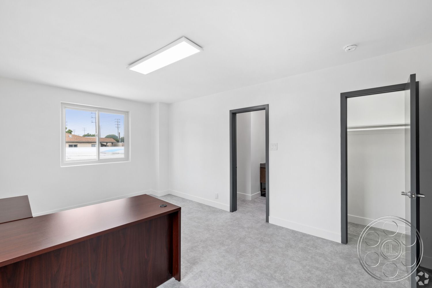 Office 125 - neutral color palette interior, white painted walls interior, floor-to-ceiling windows interior, minimalist office space interior, gray carpet flooring interior, dark wood desk interior, modern door frames interior, bright LED ceiling lighting interior, rectangular layout interior, window with city view interior, built-in closet interior