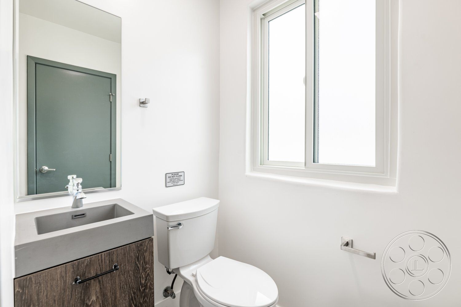 Office 125 - minimalist design elements, neutral color scheme, white painted walls, brushed steel faucet, interior powder room, concrete sink with integrated countertop, dark wood cabinet storage, framed mirror above sink, modern toilet design, energy-efficient window, wall-mounted towel holder, compact space utilization