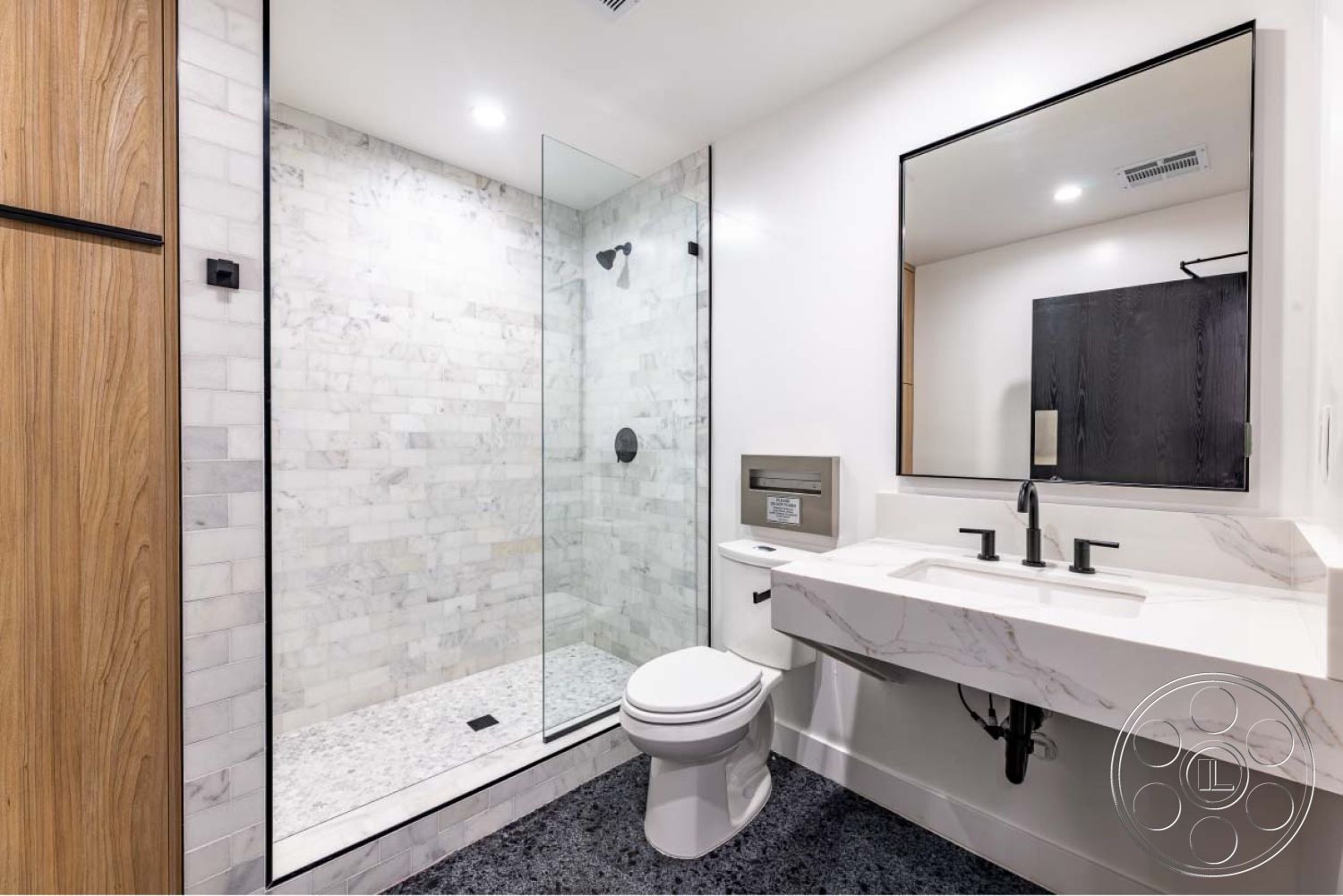 Office 125 - bathroom, interior white painted walls, interior minimalist design, interior recessed lighting, interior marble shower walls, interior glass shower doors, interior quartz bathroom countertop, interior wooden cabinet doors, interior tiled bathroom flooring, interior black fixtures, interior modern mirror, interior contrasting wood accents, interior linear drain, interior cozy bathroom setting