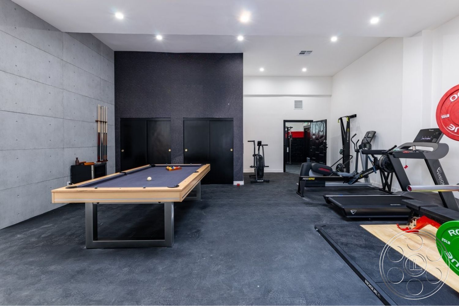 Office 125 - neutral color palette, polished concrete flooring, open space layout, minimalist design elements, exposed concrete walls, drop ceiling with recessed lighting, industrial-style lighting fixtures, black laminate cabinetry, modern black door hardware, game room with billiard table, exercise equipment area, interior fitness room, durable rubber gym flooring, wall-mounted fitness mirrors, high ceilings with subtle angles