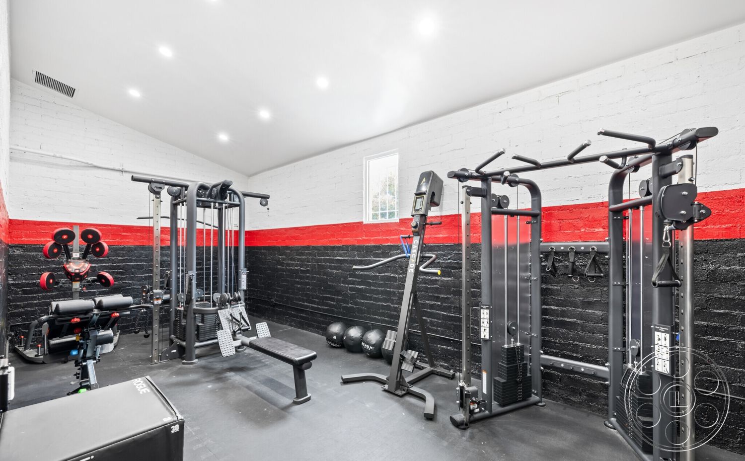 Office 125 - gym, high ceiling, gym equipment, open floor plan, track lighting, free weights, exposed brick walls, red accent wall, rubber gym flooring, black painted wall treatment, fitness room interior, cable machines, multifunctional workout bench, large window for natural light, modern gym aesthetics