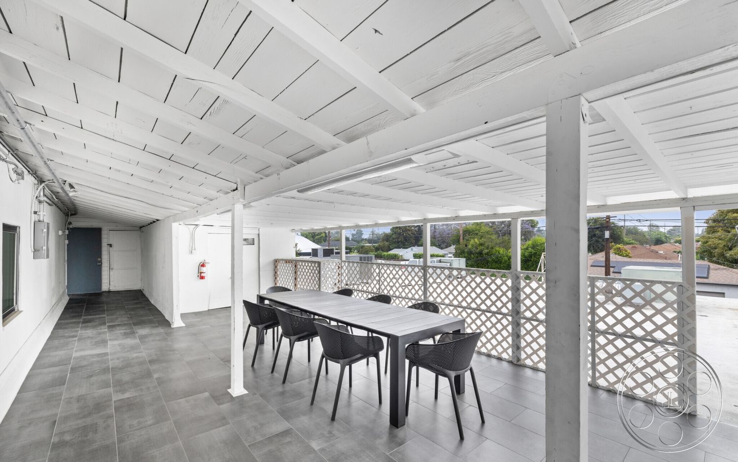 Office 125 - neutral color palette, exterior, urban skyline view, open-air patio, spacious outdoor space, natural light exposure, minimalist outdoor furniture, modern outdoor dining area, white wood beam ceiling, grey porcelain tile flooring, lattice privacy screen, contemporary exterior design, functional outdoor living area