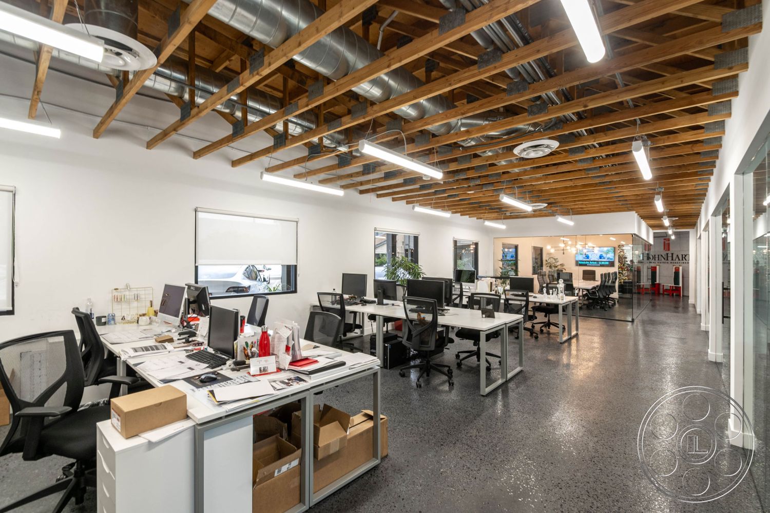 Office 126 - office, polished concrete flooring, exposed wood ceiling beams, white painted walls, decorative indoor plants, large windows for natural light, glass partition walls, minimalist design aesthetic, modern office layout, urban office setting, conference room visibility, open workspace environment, industrial ductwork, metal office furniture, black ergonomic office chairs, task lighting fixtures, reception area with seating, collaborative workstations, interior office design