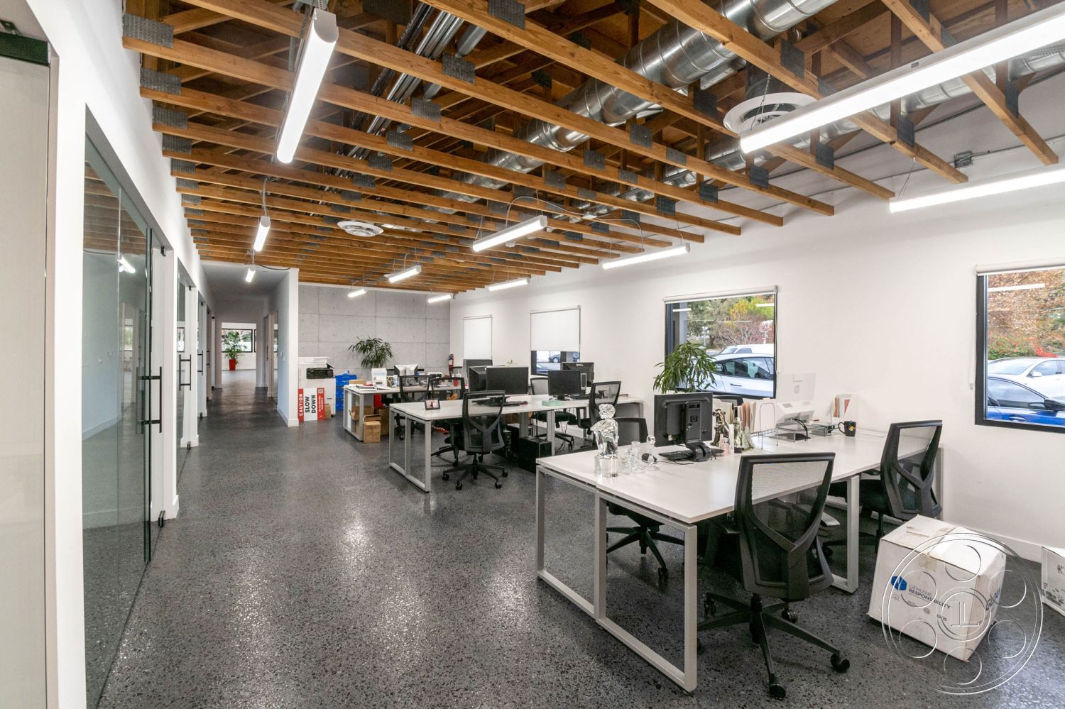 Office 126 - office, neutral color palette, plant accents, floor-to-ceiling windows, modern aesthetic, polished concrete floors, exposed wood ceiling beams, white painted walls, glass partition walls, modern office layout, industrial lighting fixtures, contemporary office furniture, functional workstations, open workspace design, interior office setting, metal ductwork ceilings