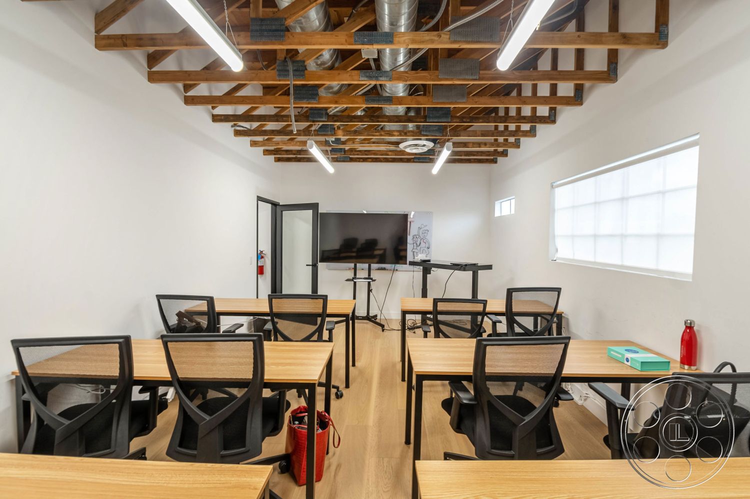 Office 126 - neutral color palette, industrial design elements, exposed ductwork, black metal light fixtures, glass window treatments, wood beam ceiling, white painted walls, polished hardwood flooring, rectangular conference tables, modern classroom layout, contemporary office chairs, digital presentation equipment