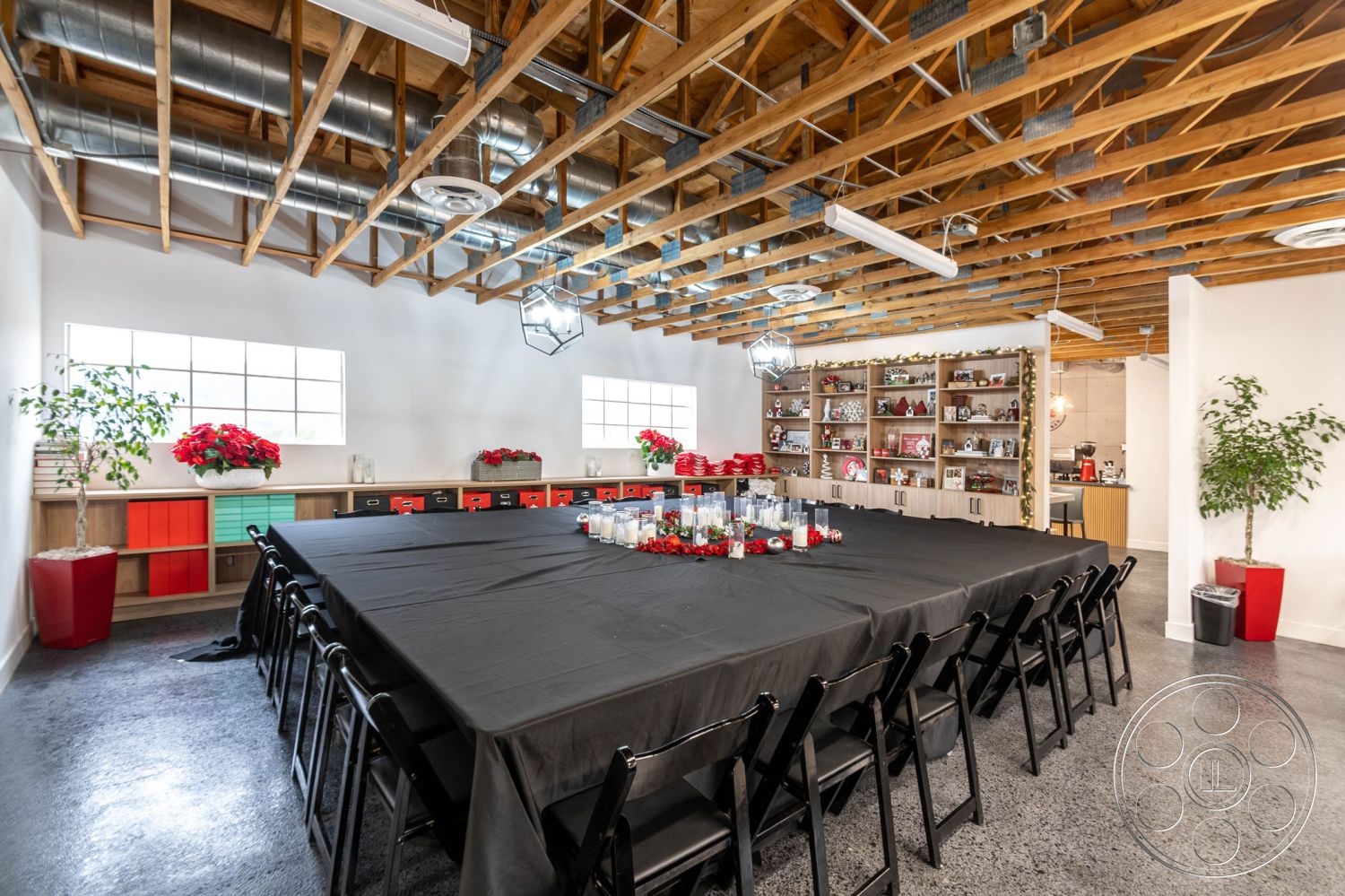 Office 126 - exposed wood ceiling beams interior, concrete floor interior, black table setting interior, square dining table interior, brightly lit meeting room interior, industrial-style window interior, open shelving units interior, plants accent interior, metal chair seating interior, modern decor interior, neutral wall color interior, ambient lighting fixtures interior, conference room layout interior, wooden cabinetry interior, colorful storage boxes interior