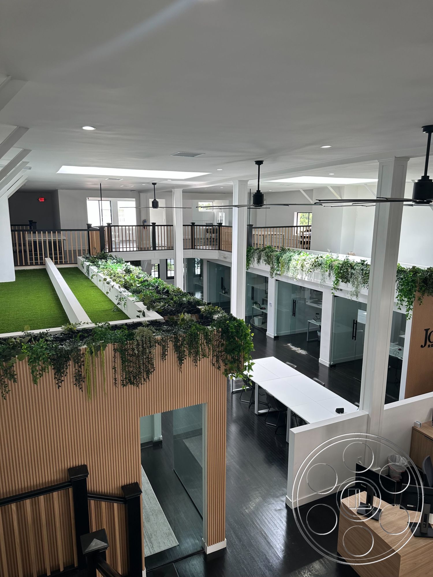 Office 127 - minimalist design, exposed beam ceiling, dark hardwood flooring, natural light from large windows, bright and airy atmosphere, glass partition walls, white painted walls, industrial style details, open concept office layout, potted greenery accents, elevated green space, wood feature walls, modern ceiling fan fixtures, flexible workspaces, collaborative seating areas, carpeted conference rooms, sustainable materials usage, multi-level office design, creative workspace environment