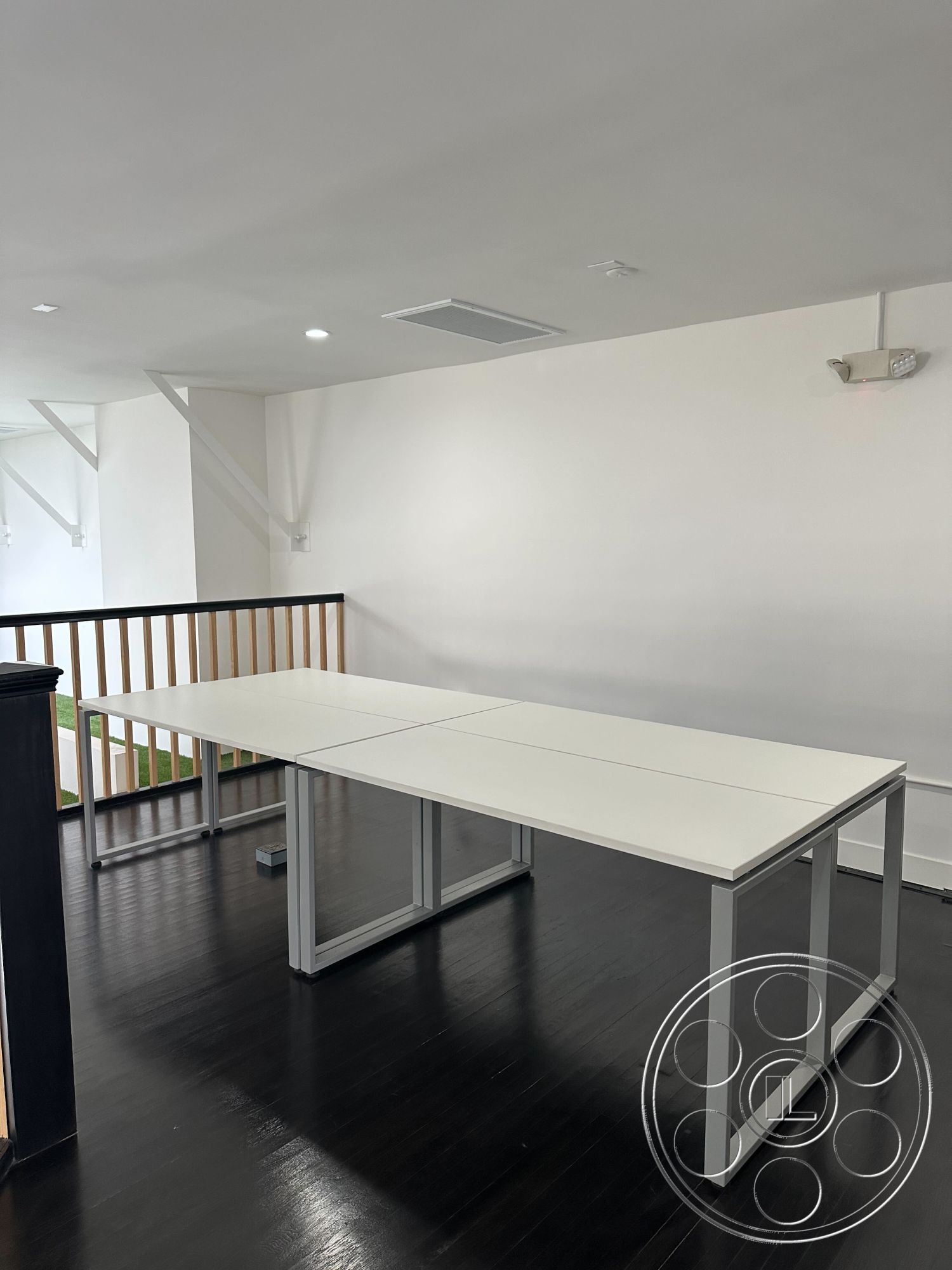 Office 127 - recessed lighting, bright natural light, minimalist design elements, neutral color scheme, black hardwood flooring, white painted walls, open layout design, modern office space, metal frame tables, slatted wood railing