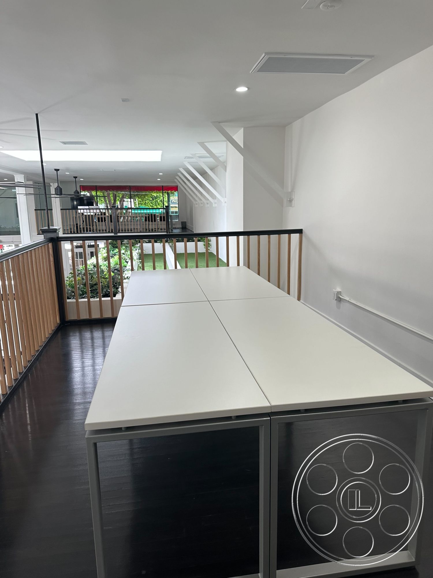 Office 127 - neutral color palette, contemporary decor, open concept layout, black hardwood flooring, interior minimalist design, modern architectural details, white laminate table surface, exposed wood railing, soft natural lighting from skylight, cylinder ceiling recessed lights, indoor greenery visible