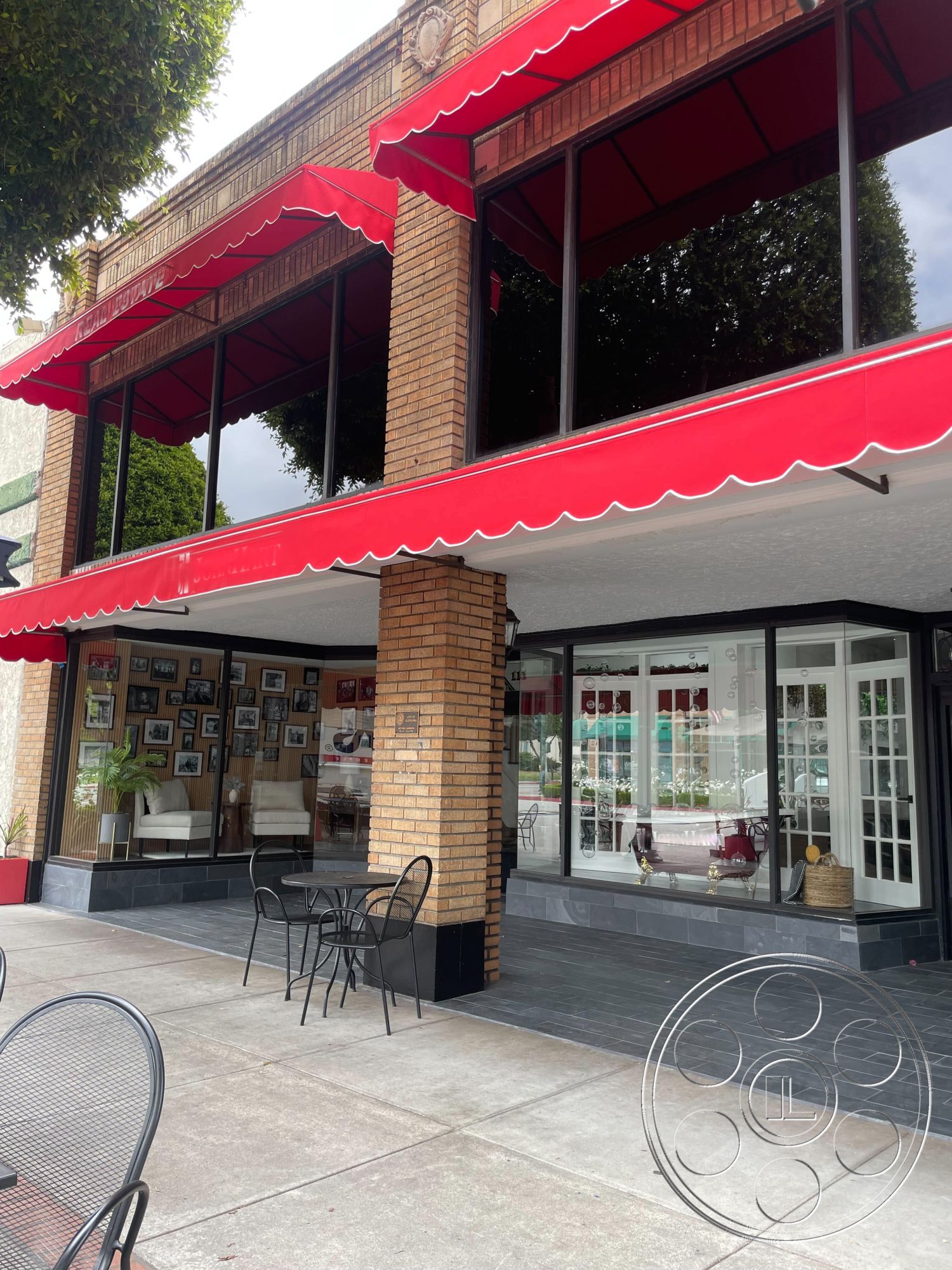 Office 127 - slate stone flooring, urban setting, patio seating area, glass storefront windows, exposed brick columns, brick facade exterior, red awning overhangs, black painted iron railing, modern outdoor tables and chairs, decorative planting beds, historical architectural details, retail space exterior, commercial building features