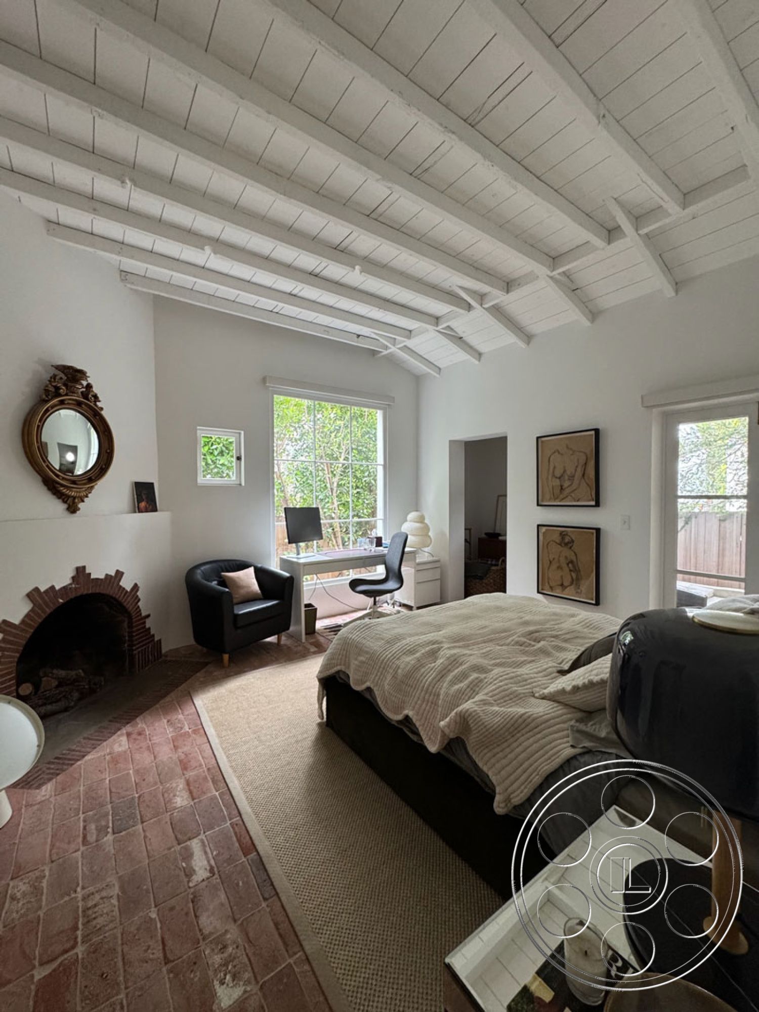 Spanish 165 - hardwood bedroom floors interior, neutral color palette interior, exposed wood ceiling beams interior, textured plaster walls interior, contemporary design elements interior, brick fireplace surround interior, large window view of greenery interior, minimalist desk workspace interior, plush bedding interior, modern chair design interior, area rug over hardwood floors interior, decorative mirror accent interior, light-filled bedroom interior, simple artwork decor interior
