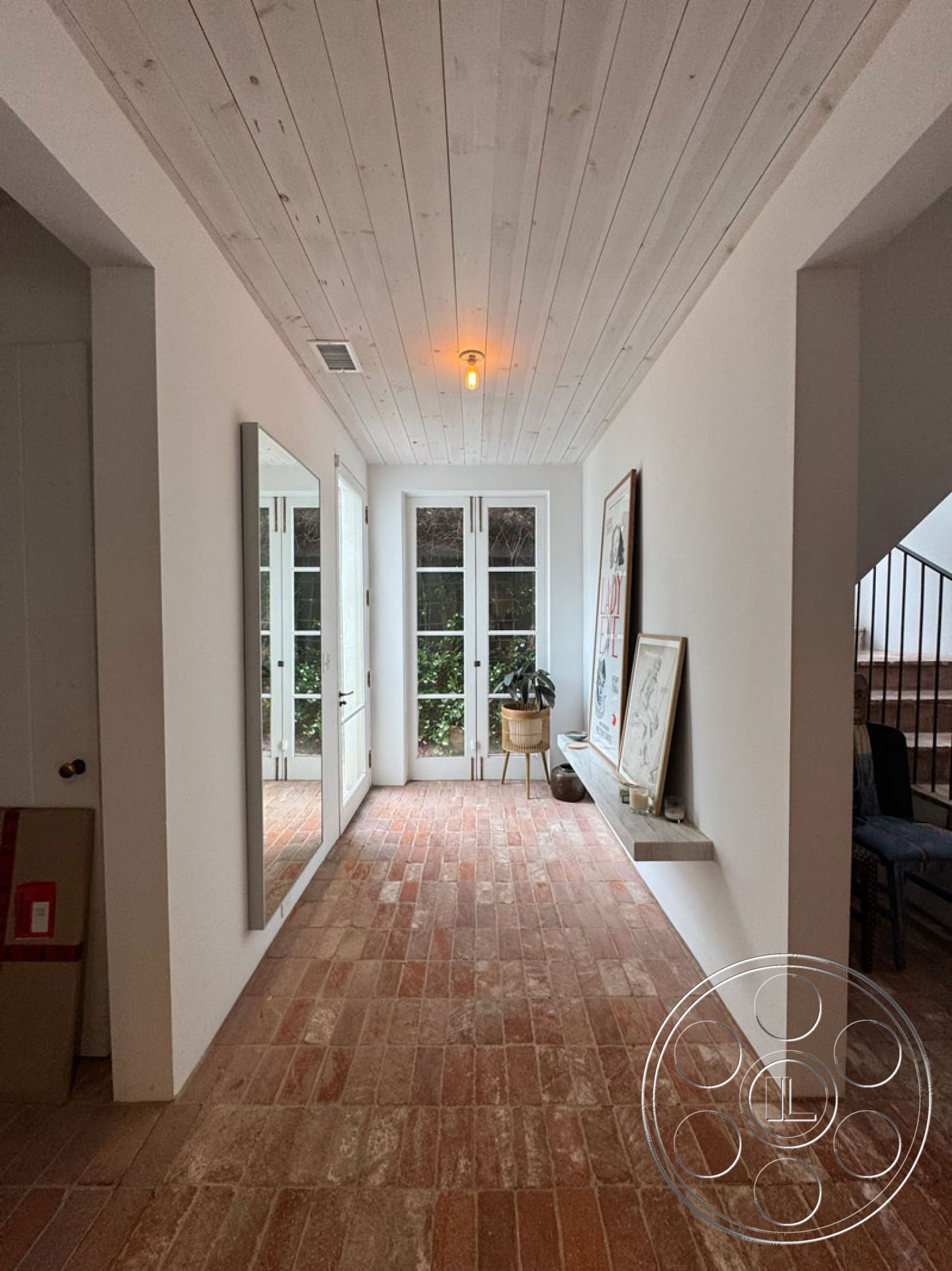 Spanish 165 - open space layout, floor-to-ceiling windows, interior hallway, modern minimalist design, white painted walls, contemporary art display, exposed wood ceiling boards, red brick entryway flooring, natural light entry hall, simple wooden cabinetry, indoor plant placement, symmetrical room design