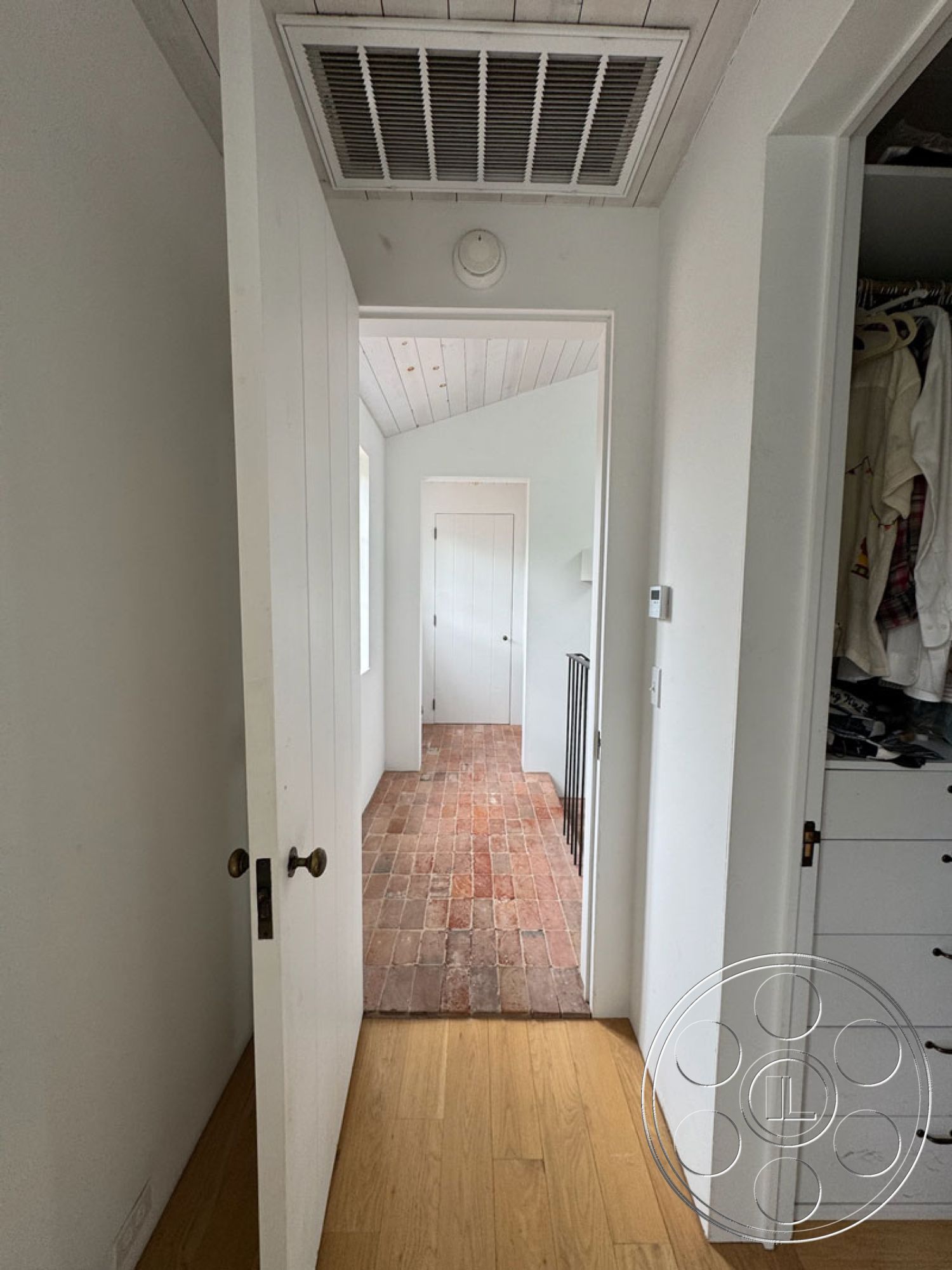Spanish 165 - transitional style, modern interior design, solid wood door, white painted walls, minimalist hallway, wood plank ceiling, wall-mounted air vent, exposed brick hallway flooring, natural hardwood flooring