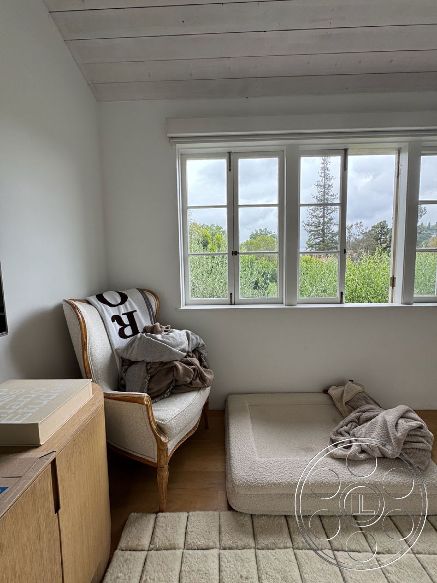 Spanish 165 - minimalist decor, neutral color palette, hardwood flooring, soft area rug, natural light from large windows, textured throw blankets, interior bedroom, white painted walls, exposed wood ceiling planks, double-hung window design, decorative armchair with upholstery, cozy sitting nook