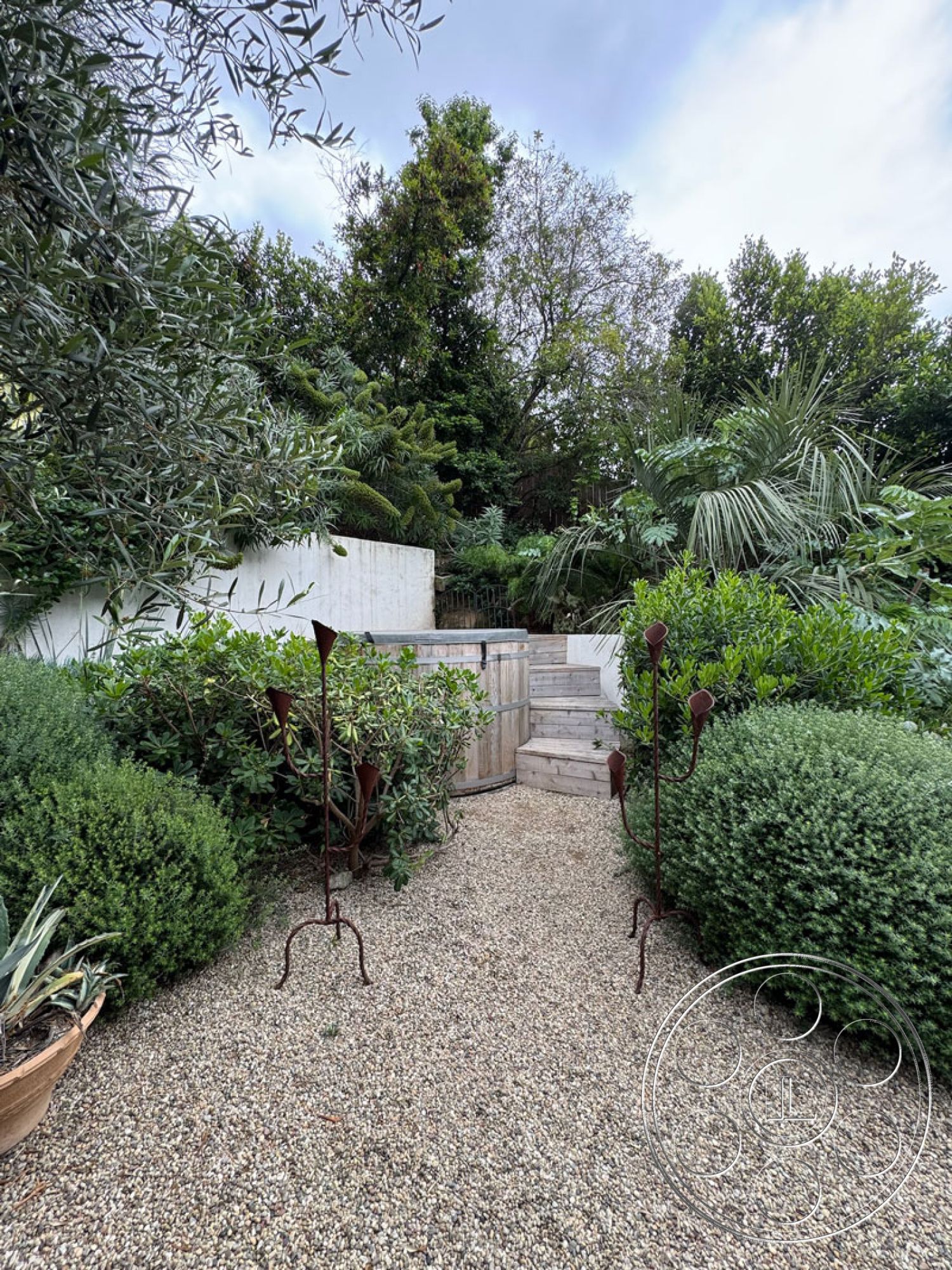 Spanish 165 - natural stone elements, wooden steps, concrete wall, gravel pathway, lush tropical landscaping, modern garden design, textured greenery, rustic outdoor decor, outdoor garden setting, metal garden sculptures, rounded shrubbery, exterior steps, varied plant species, multi-level landscape