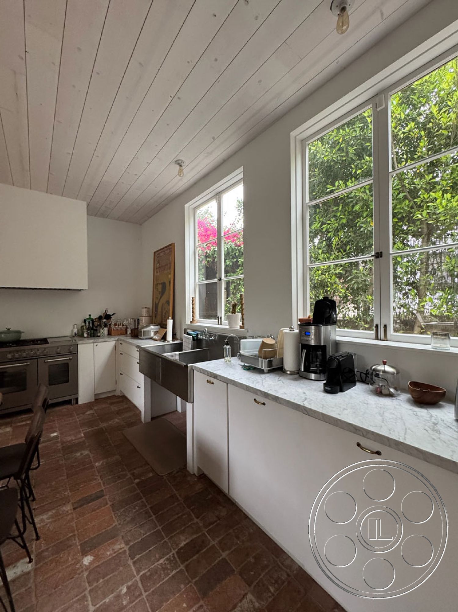 Spanish 165 - stainless steel kitchen appliances, marble kitchen countertops, interior kitchen with white painted walls, exposed wood ceiling with shiplap finish, brick flooring in kitchen, double-hung windows with garden view, modern kitchen cabinetry with minimalist handles, open layout kitchen space, natural light-filled kitchen environment, rustic kitchen design elements