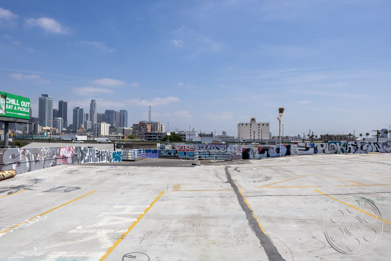 Rooftop 51 - urban skyline view, graffiti wall art, concrete rooftop deck, commercial building setting, industrial exterior, concrete pavement surface, city balcony, open-air parking structure, steel light fixtures, brightly painted signage