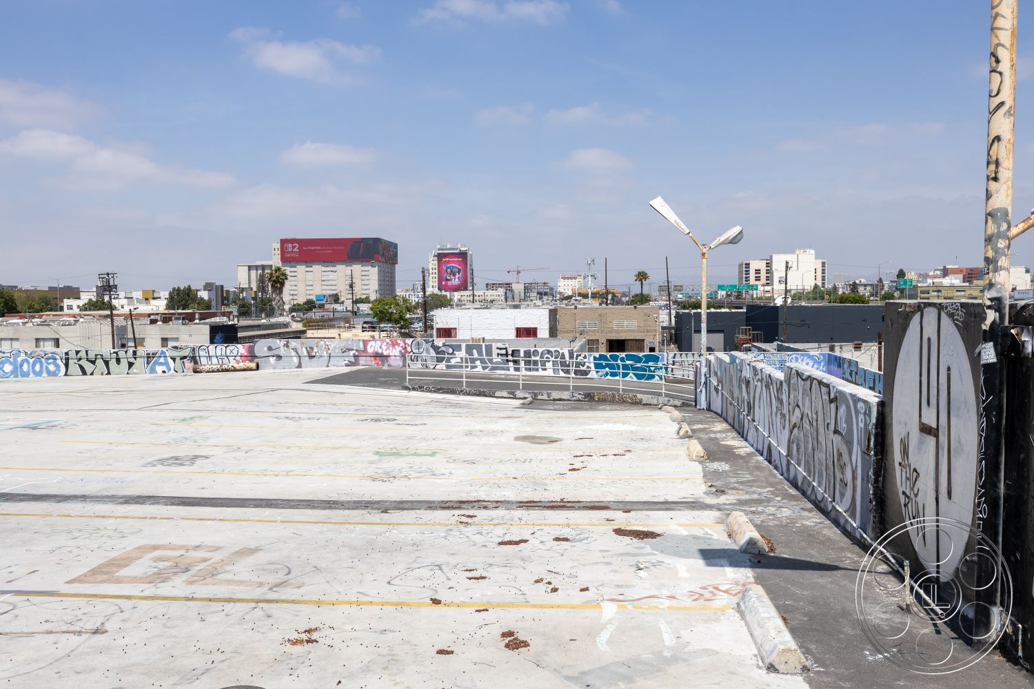 Rooftop 51 - city skyline view, flat roof design, urban rooftop setting, industrial urban environment, exposed concrete rooftop surface, graffiti wall art treatment, metal railing surrounds, commercial building structure, concrete parking area, weathered metal surfaces