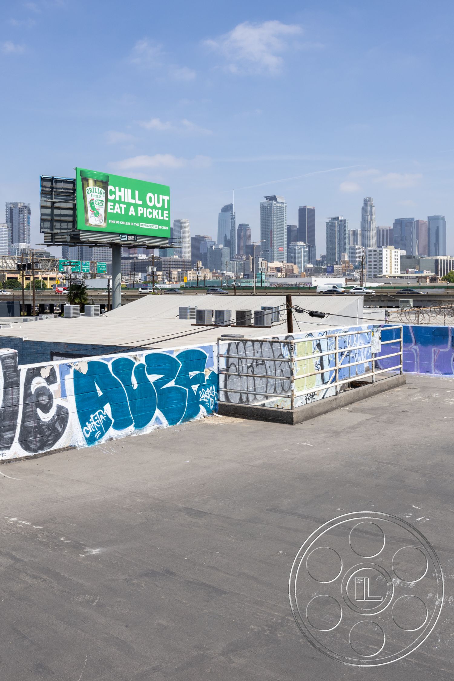 Rooftop 51 - urban landscape, city skyline view, open-air terrace, graffiti wall art, industrial setting, flat roof design, commercial building exterior, billboard signage, urban rooftop space, roof deck exterior, concrete floor surface, metal railing with graffiti, skyline background
