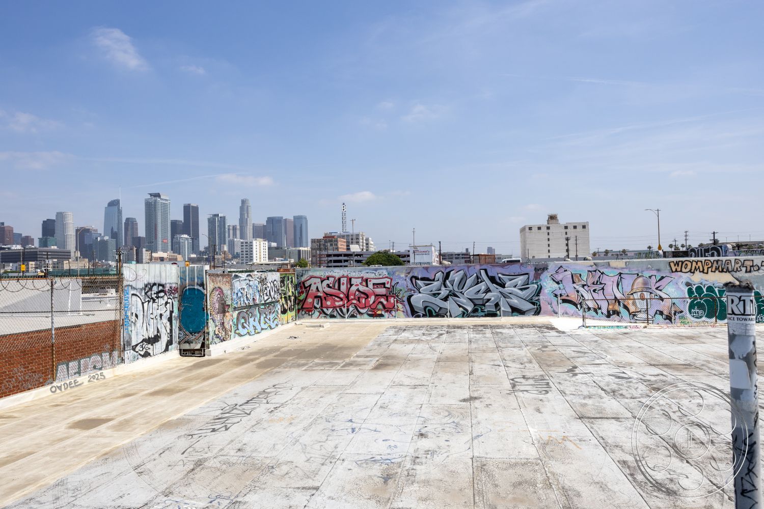 Rooftop 51 - open-air space, urban skyline view, industrial-style architecture, concrete slab flooring, exterior rooftop space, graffiti-covered walls, concrete rooftop surface, metal chain-link fencing, weathered brick wall, sprawling cityscape backdrop, artistic urban expression, textured rooftop surface, urban environment setting, downtown skyline, public urban art, street art murals, vintage industrial vibe